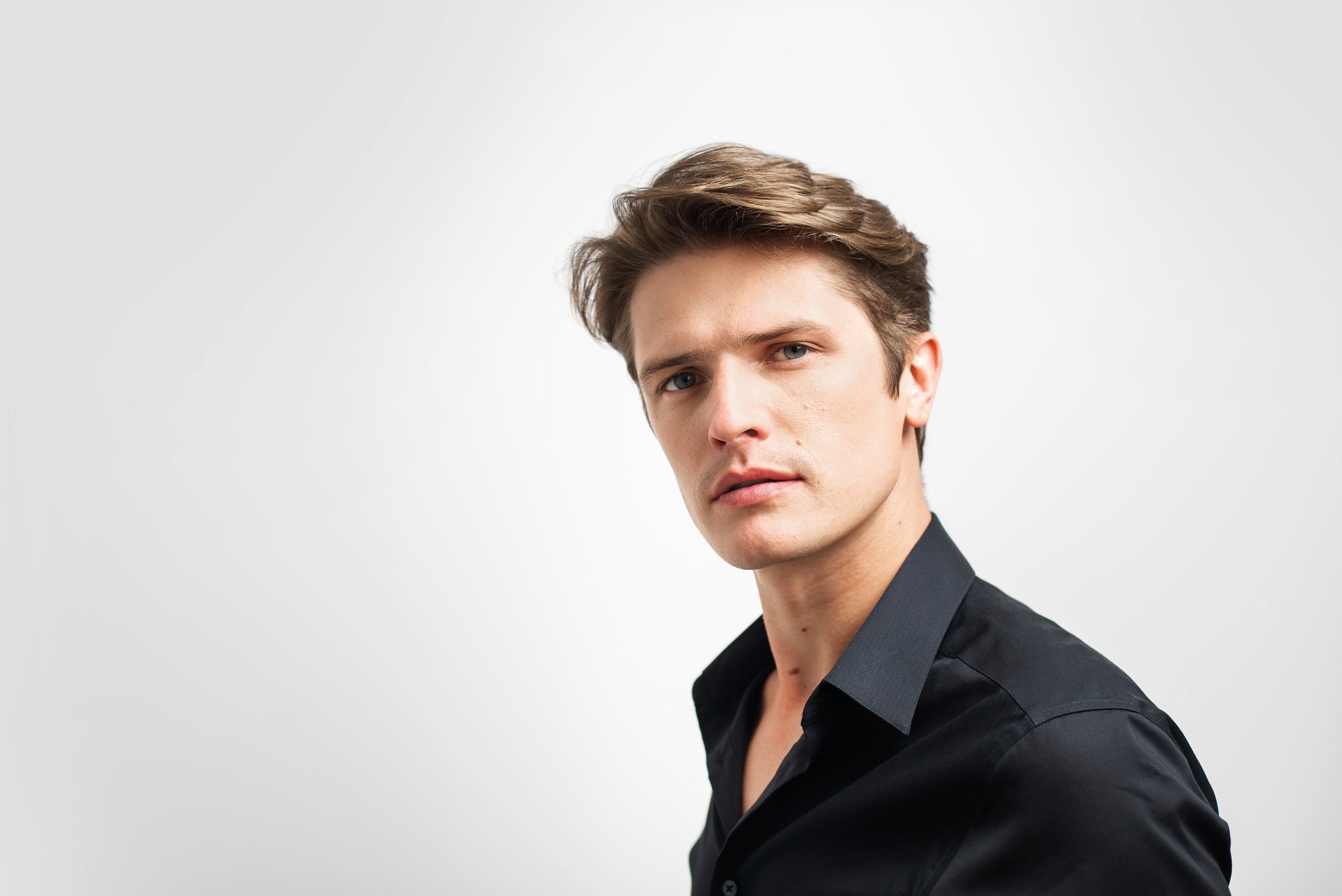 Portret mężczyzny w czarnej koszuli na jasnym tle