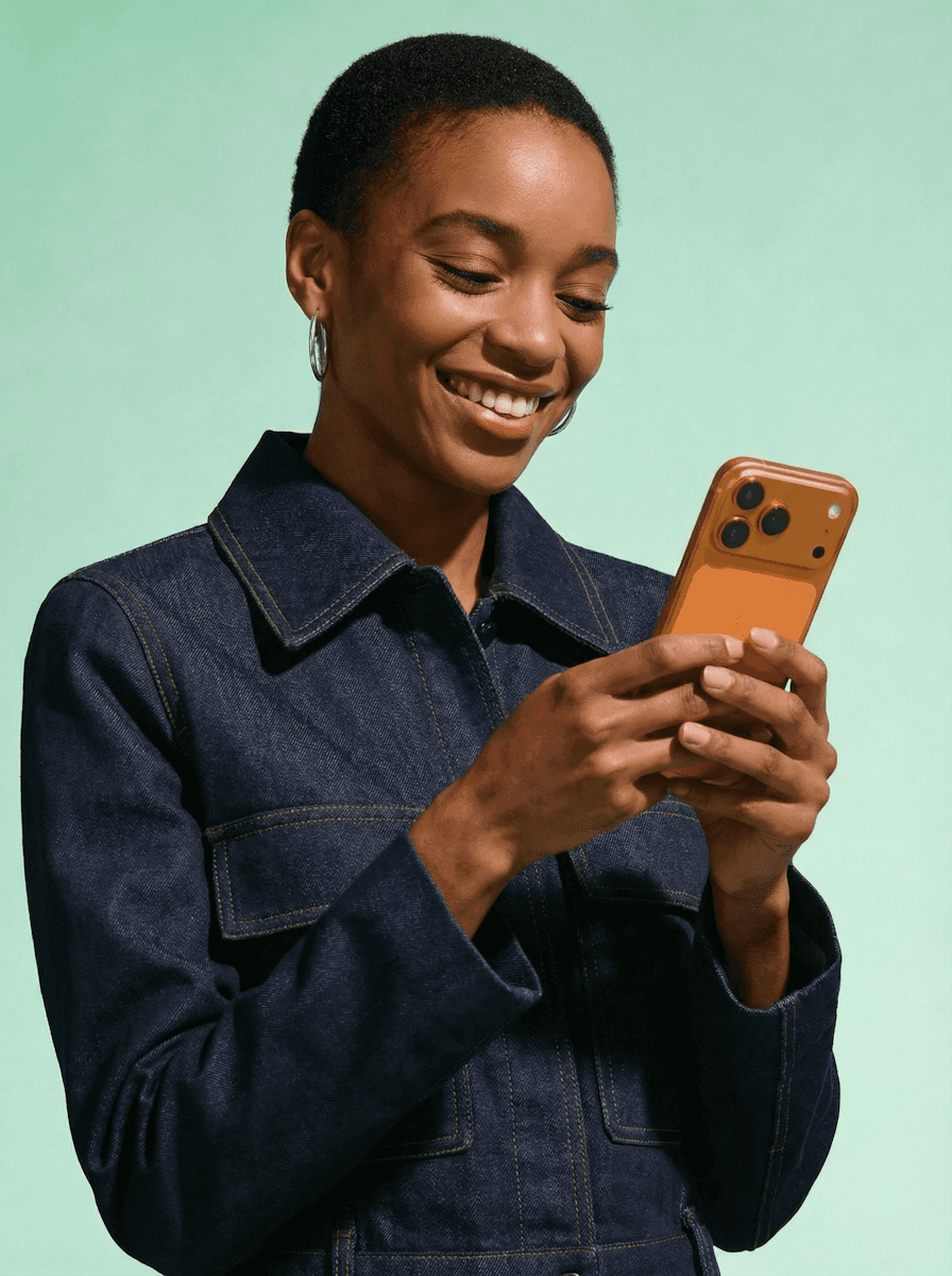 Woman smiling at orange smartphone.