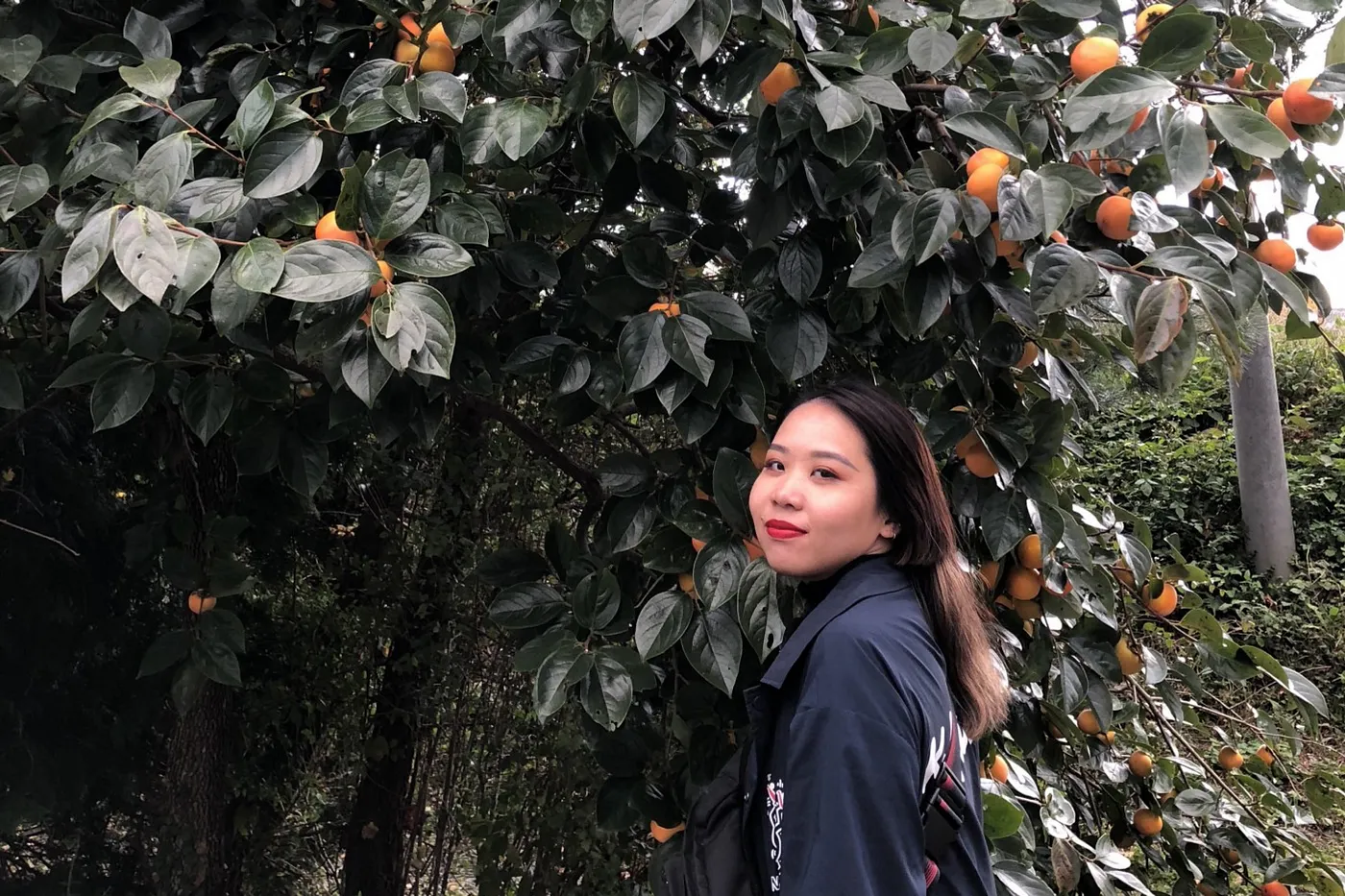 A photo of Adeline against an orange tree.