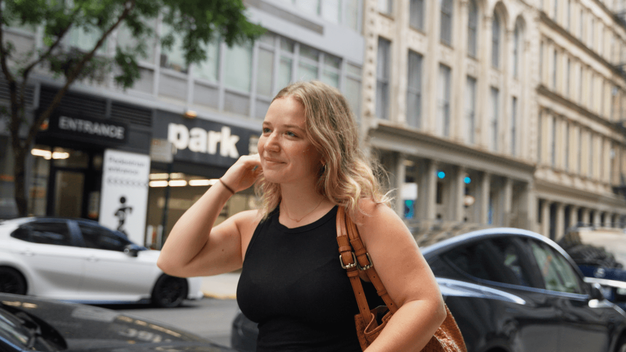 A blond woman walking in the street with buildings in the background