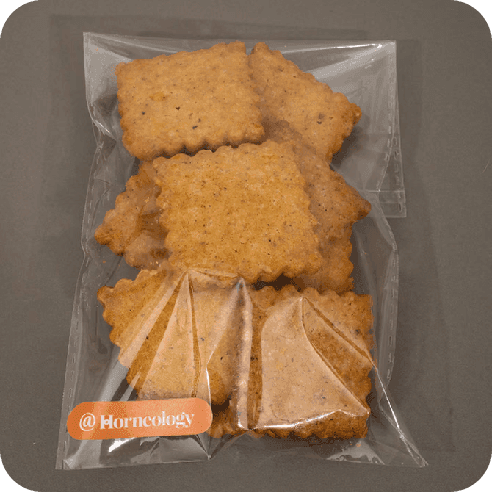 Galletas especuloos cuadradas con borde festoneado en empaque sellado transparente.