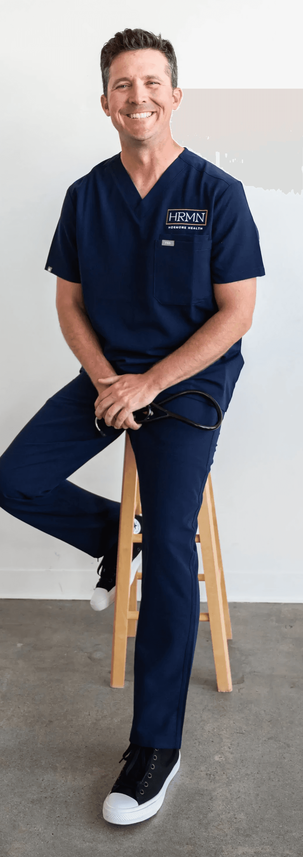 Portrait of Jamie Ruiz, a certified Physician Associate, smiling in a professional medical setting with shelves of supplements and medical products in the background.
