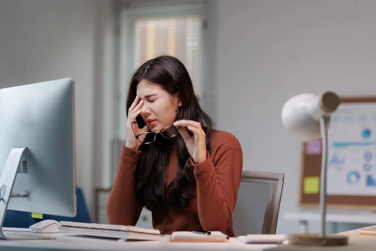 Mulher com incômodo nos olhos durante o trabalho no computador