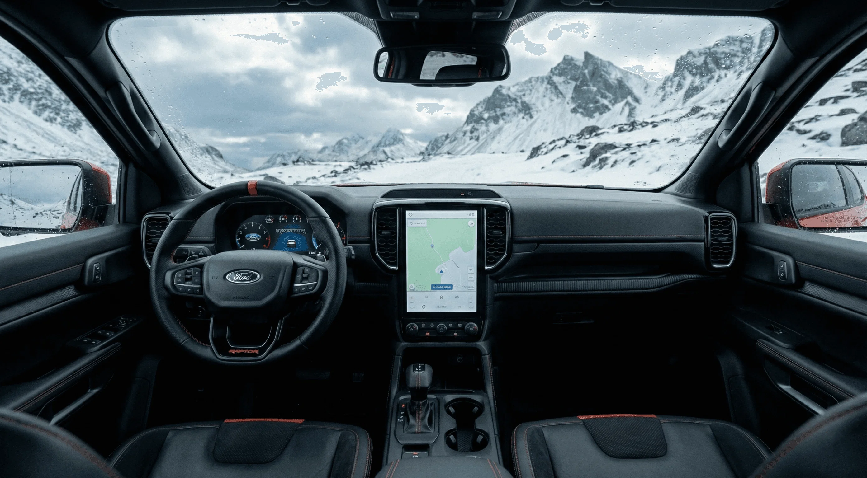Interior view of a Ford Ranger Raptor showing the dashboard and steering wheel with snowy mountains visible through the windshield.