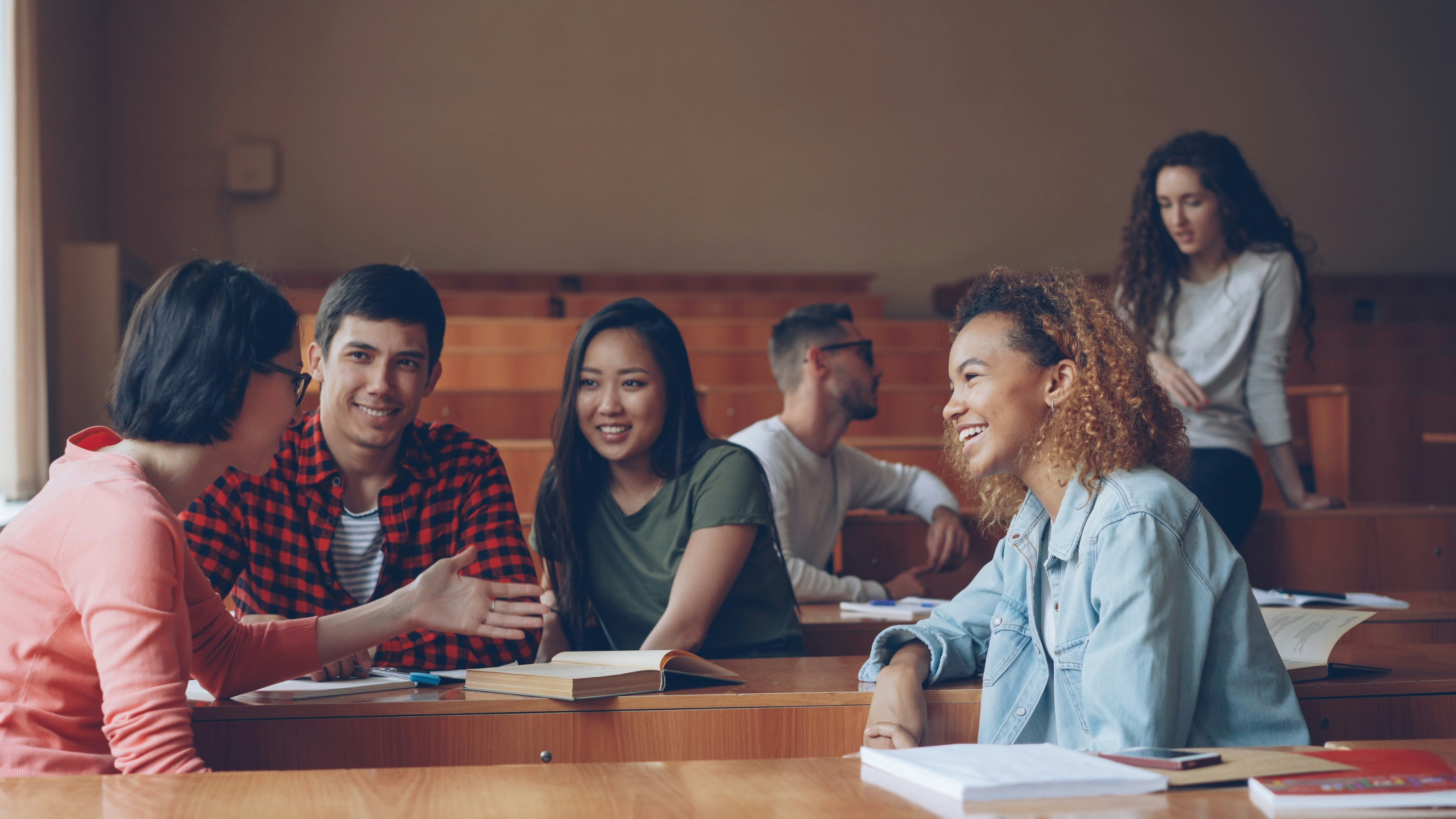 Students talking and laughing in a lecture hall.