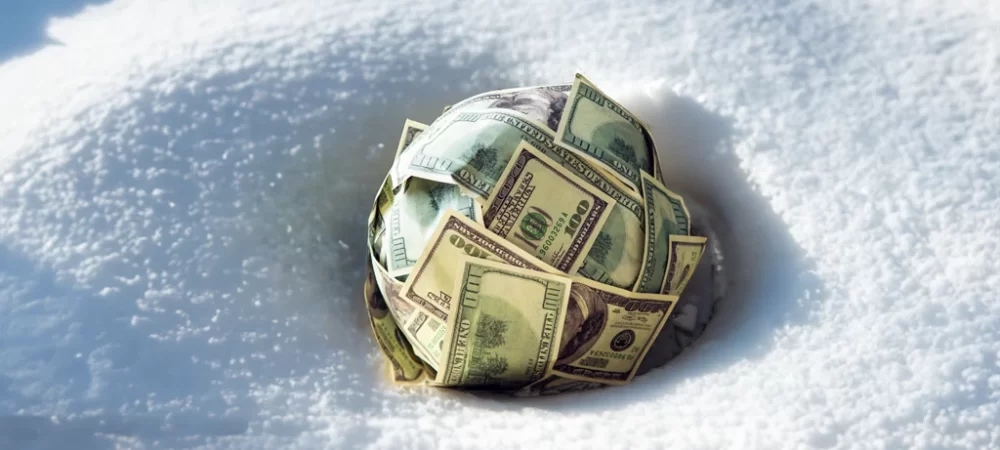 Money budnled in snow, showcasing the snowball effect of compounding through simple investing 