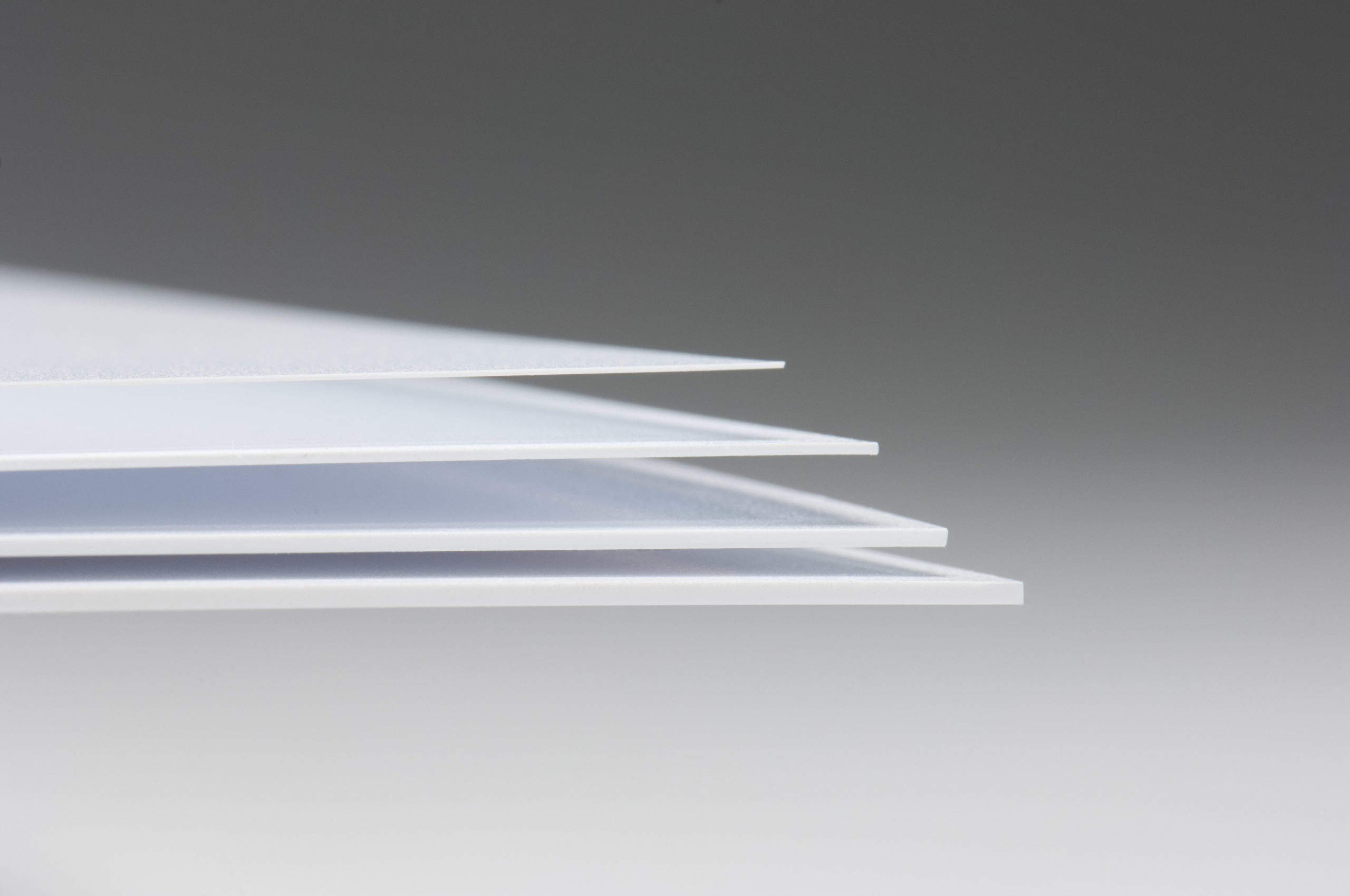 Lembaran bahan HIPS (High Impact Polystyrene) berwarna putih dan solid tersusun rapi di area penyimpanan pabrik