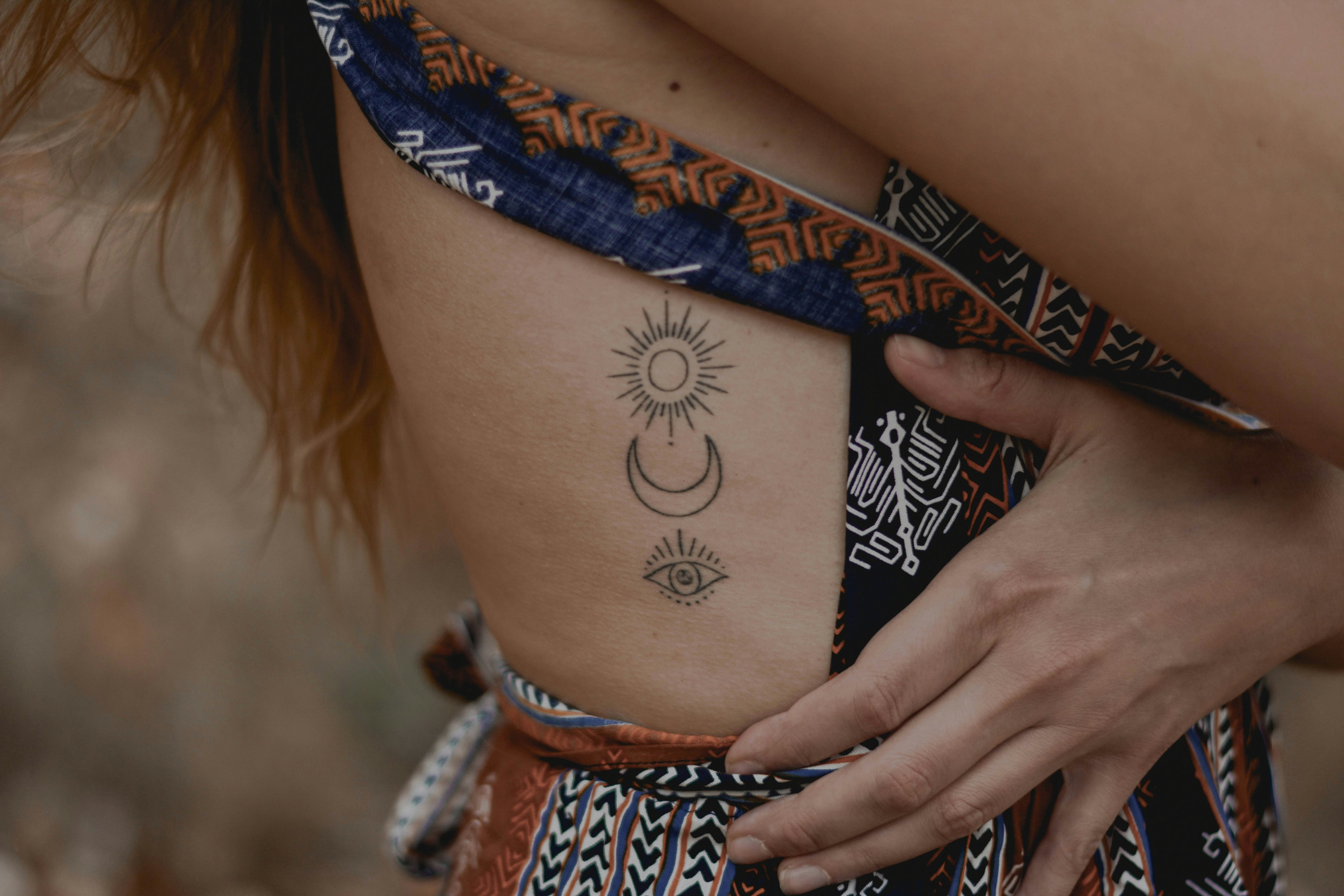 A lone green tree standing in a yellow field with birds flying in the background on a clear day