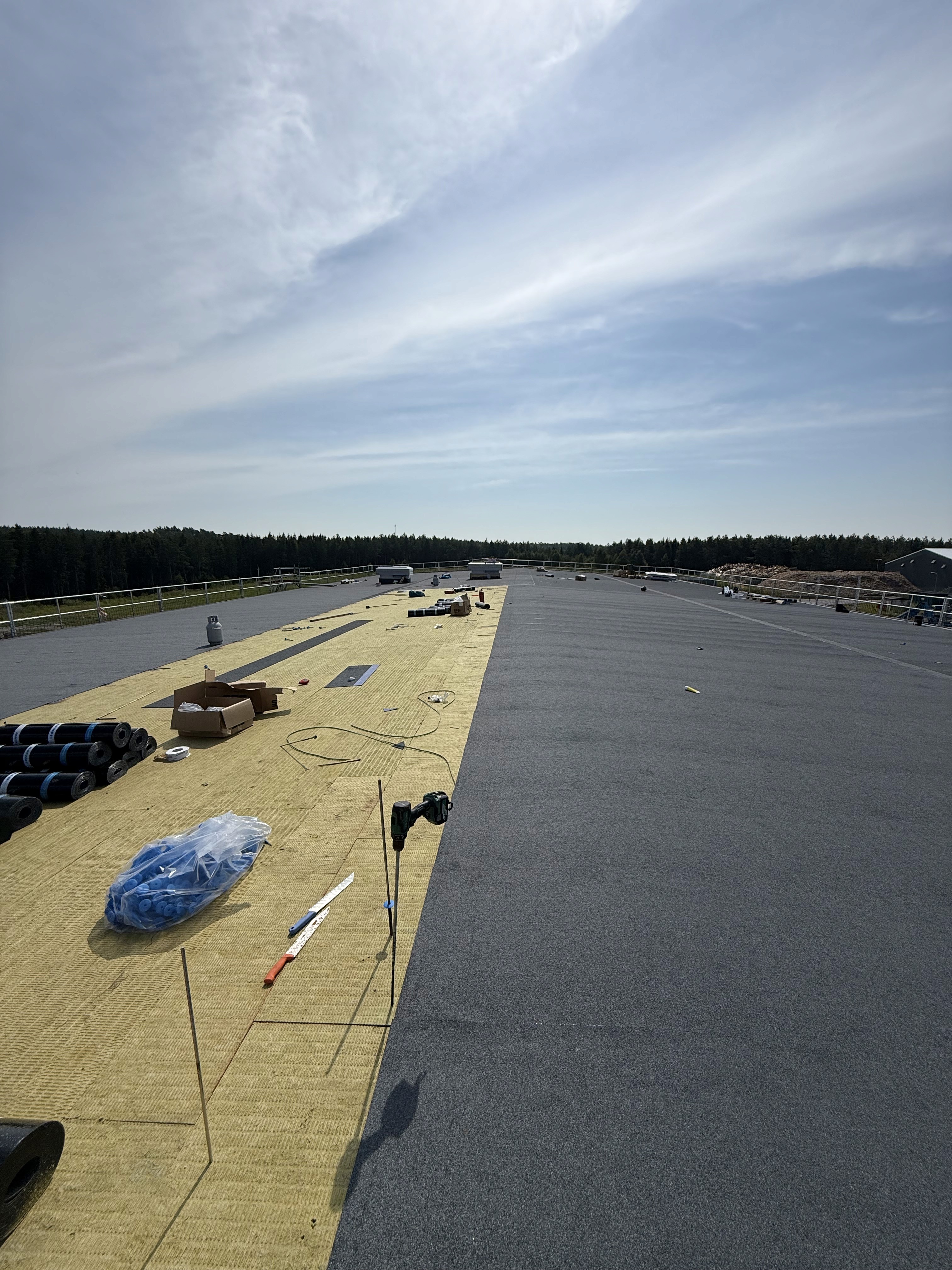 View across the roof with insulation and membrane under a clear blue sky