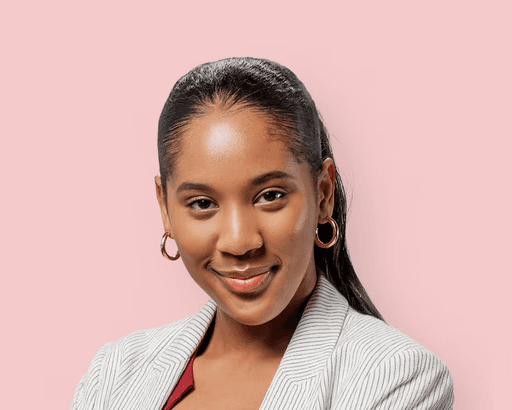 Smiling Black woman wearing a pinstriped blazer and gold hoop earrings against a solid pink background.