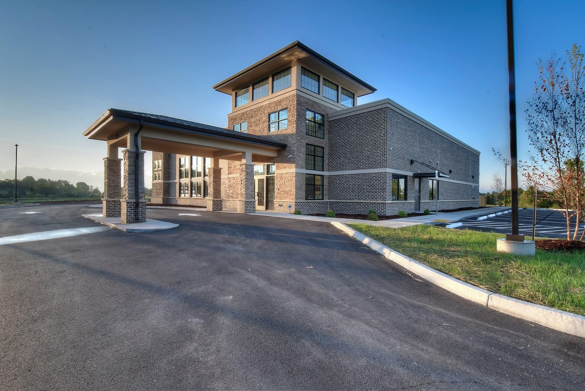 Modern building exterior with a sloped roof, entrance, and well-maintained landscaping on a clear day.