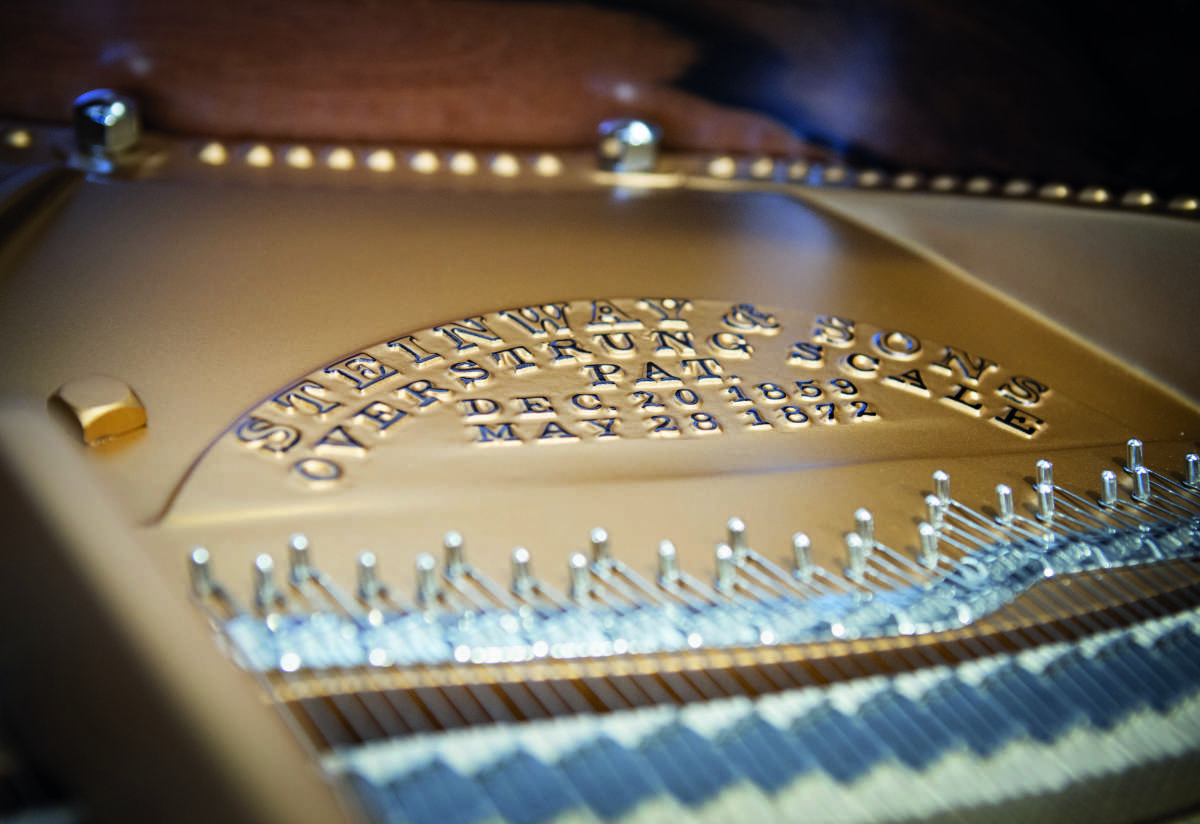 A macro shot of the golden frame and strings inside the Steinway & Sons grand piano, showing the immaculate restoration work.