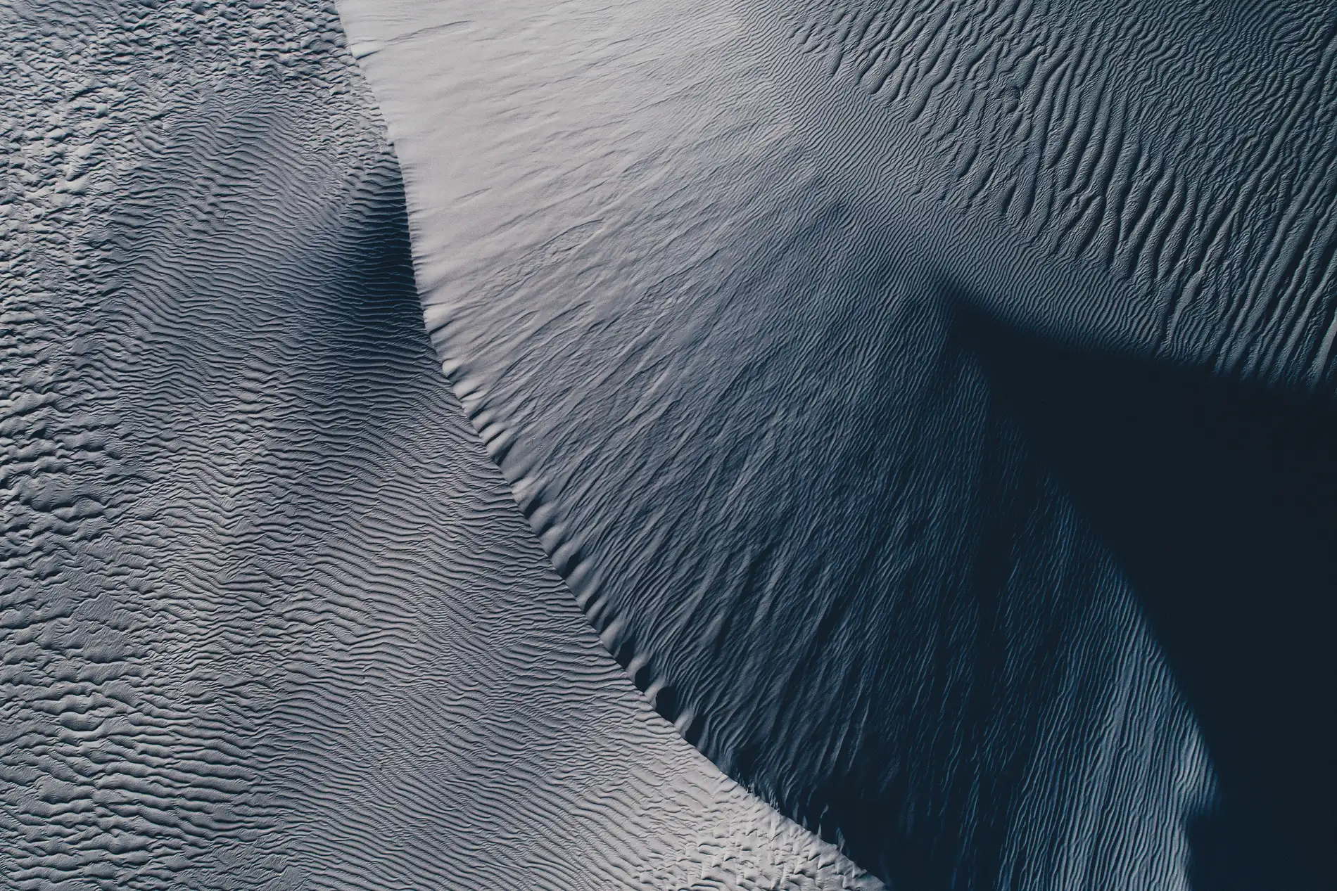 Aerial of the crest of a white sand dune in raking light