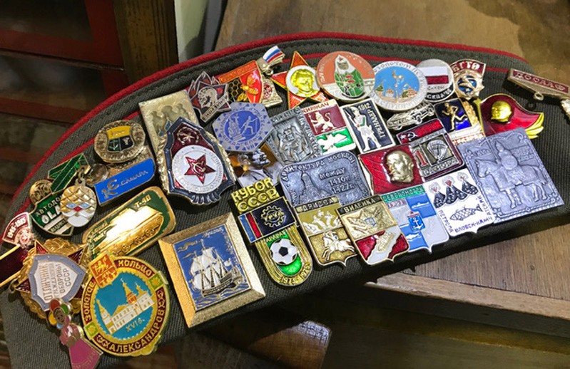 A photo of a piece of green and red clothing, army looking, filled with different kind of embossed and colored badges.