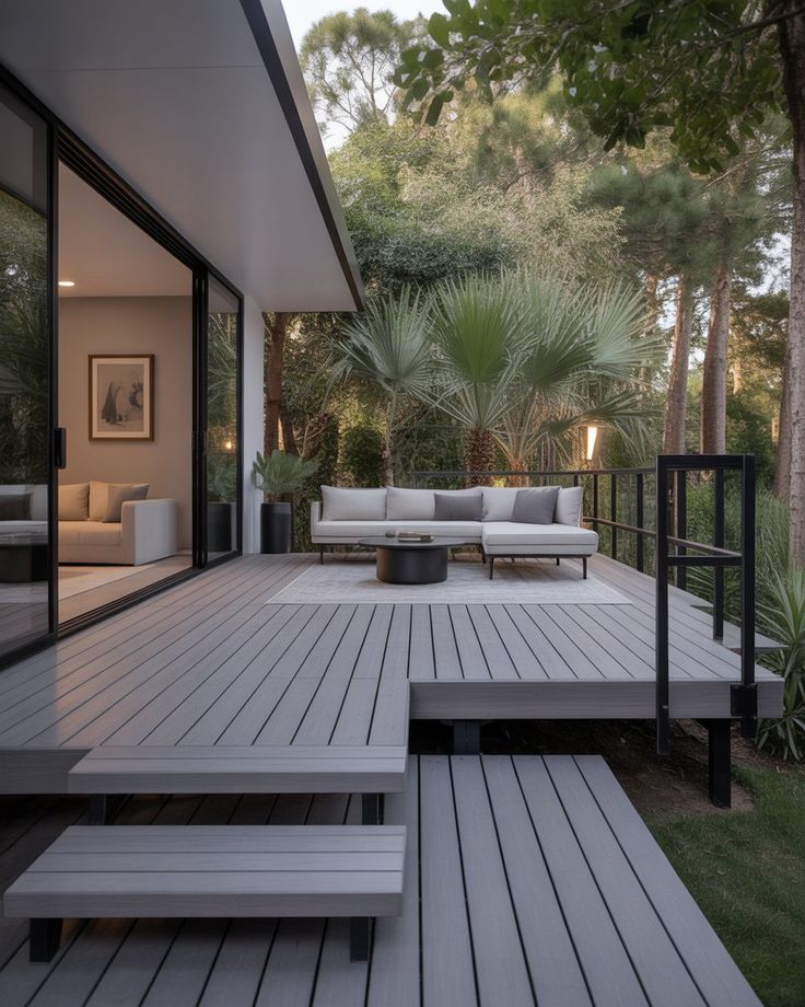 A serene outdoor lounge area with two chairs surrounded by lush greenery and natural light streaming in.