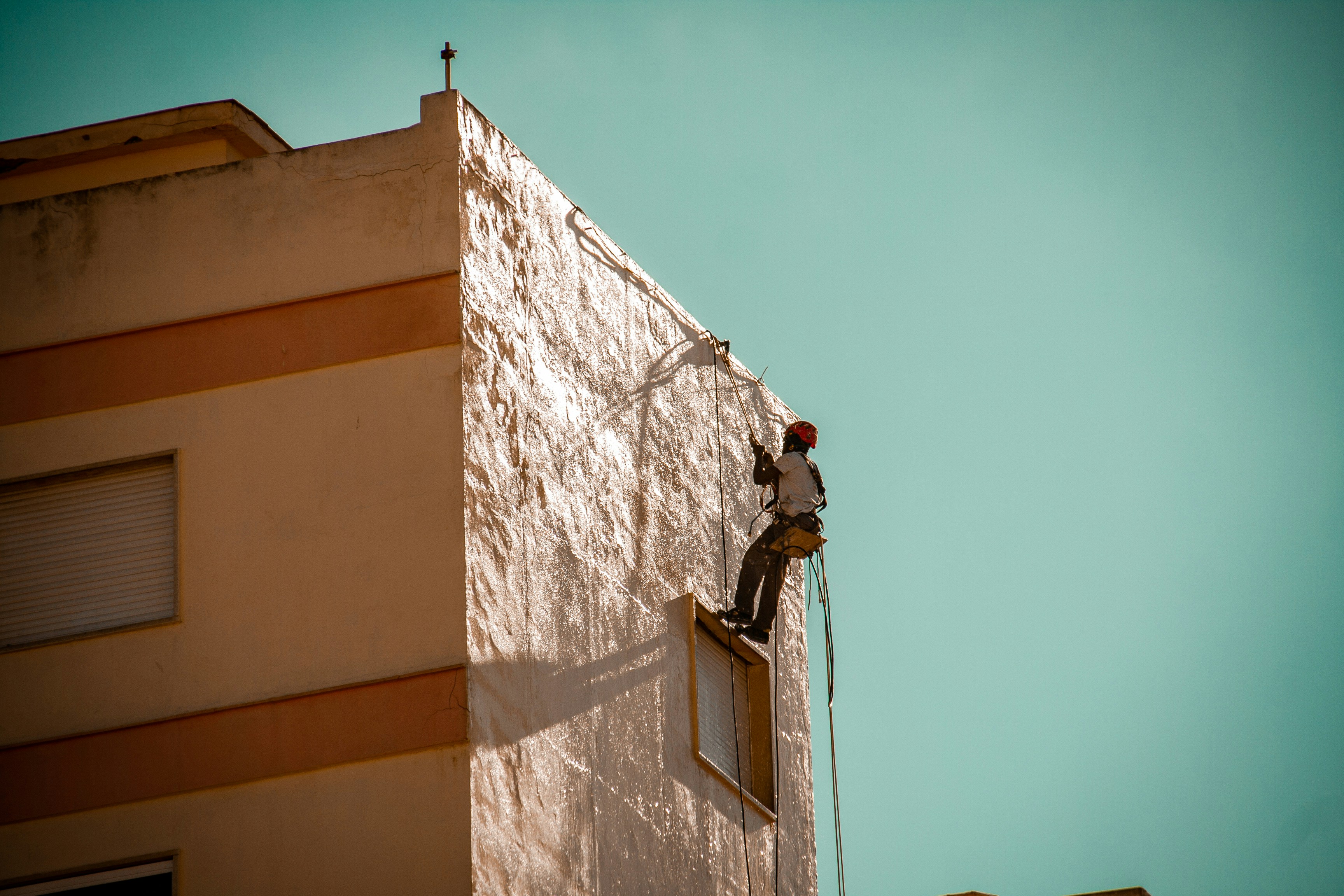 a man on a ladder working on the side of a building