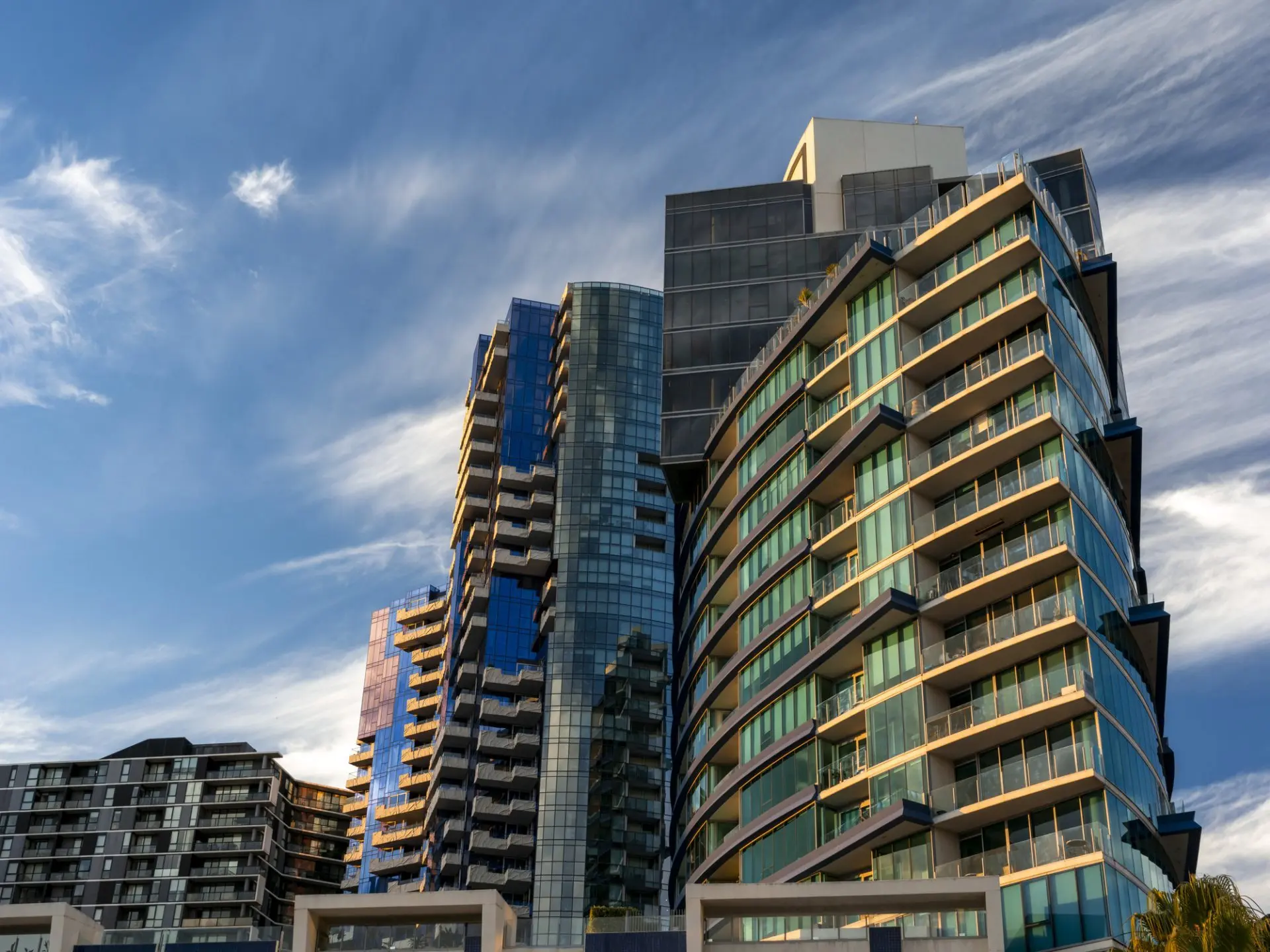 Modern apartment buildings against a cloudy blue sky.