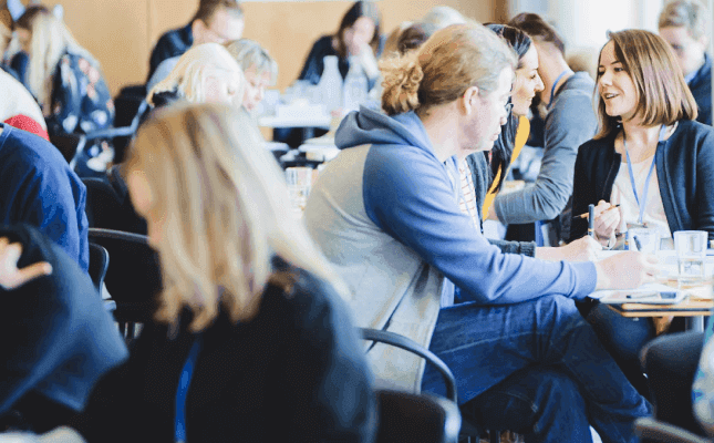 Workshop participants collaborating at tables during a Design Sprint facilitation session