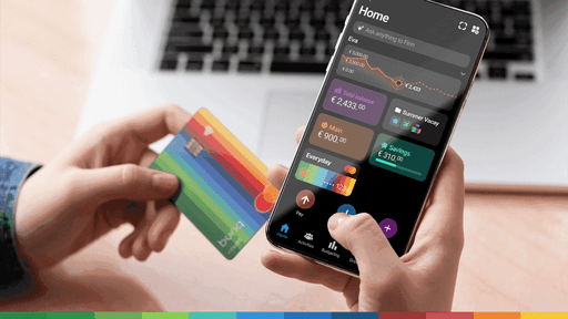 A person holds a credit card in one hand and a smartphone displaying apps in the other, with a laptop in the background.