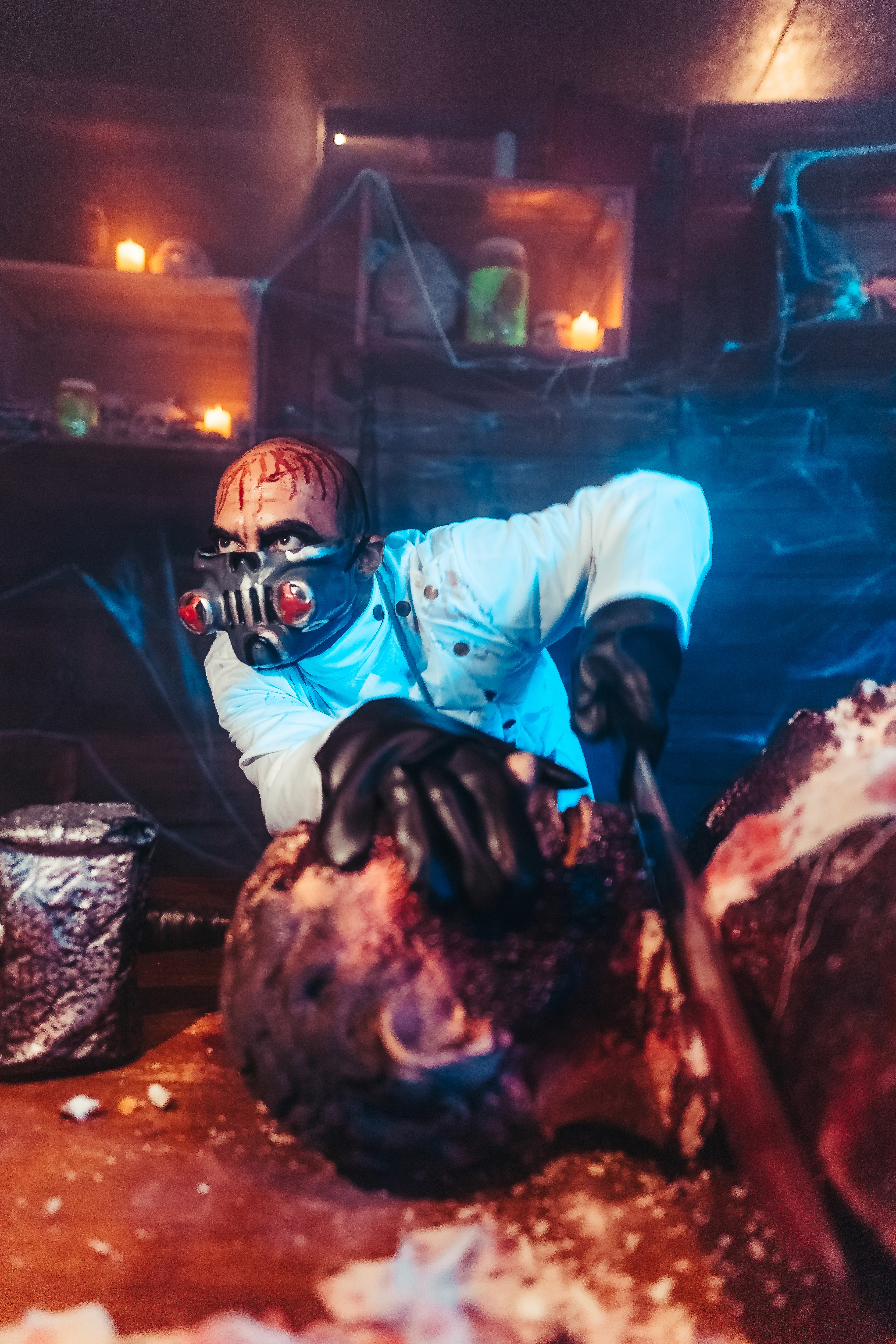Masked butcher scare actor in white chef costume with fake body props and haunted set design at Dubai Halloween event