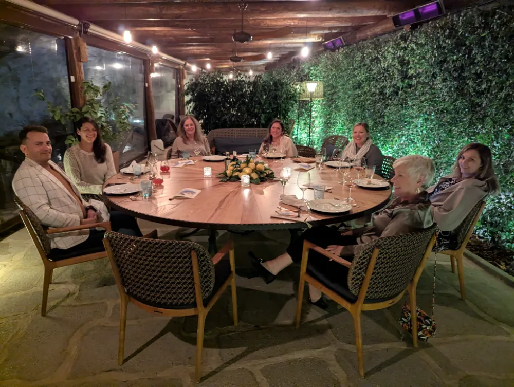 Guests at a round table under a lit pergola at Monastero Santa Rosa in the evening.