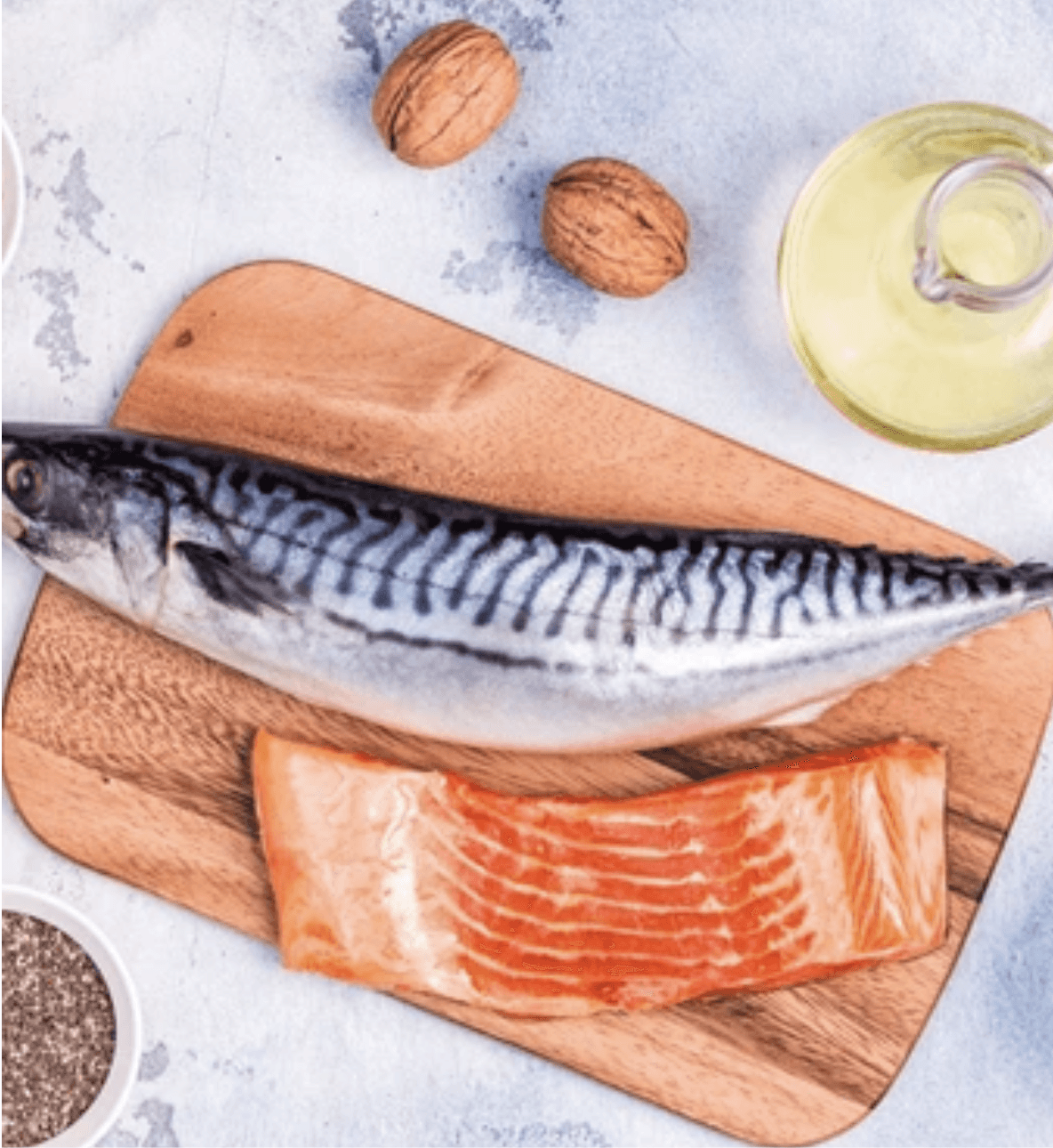 A Picture of salmon and a salmonon a cutting board alonside oil and a couple walnuts