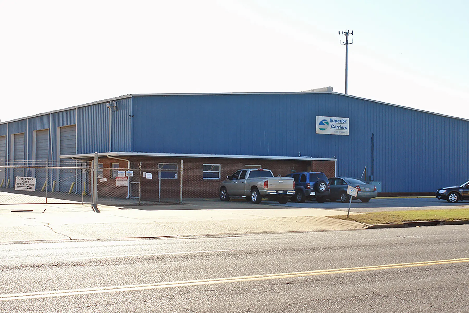 Blue metal truck terminal building at Heniff Transportation with a paved yard