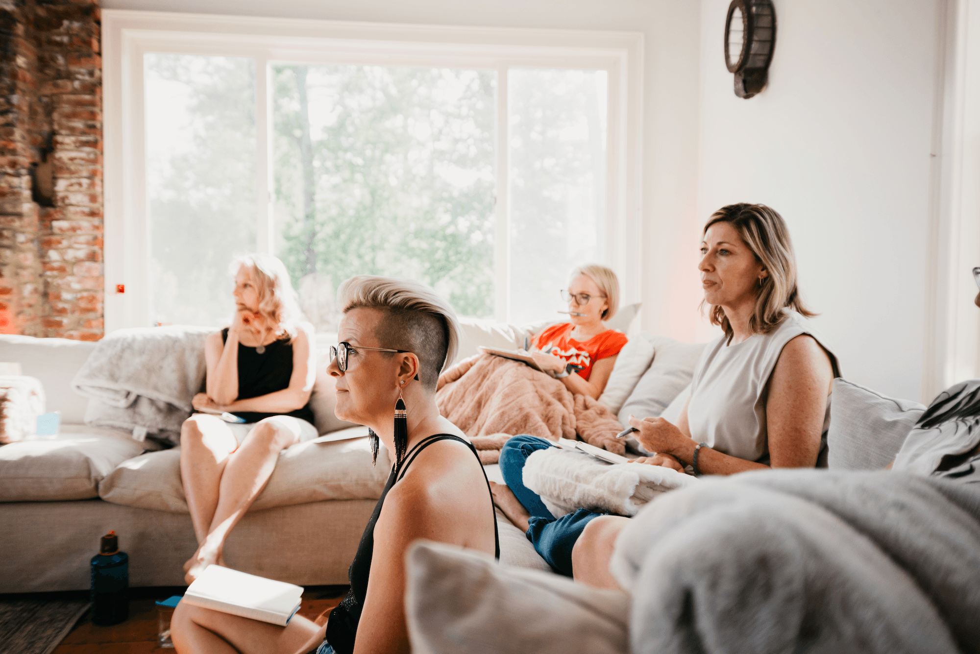 Three people sitting on a couch in a room looking at mobile devices