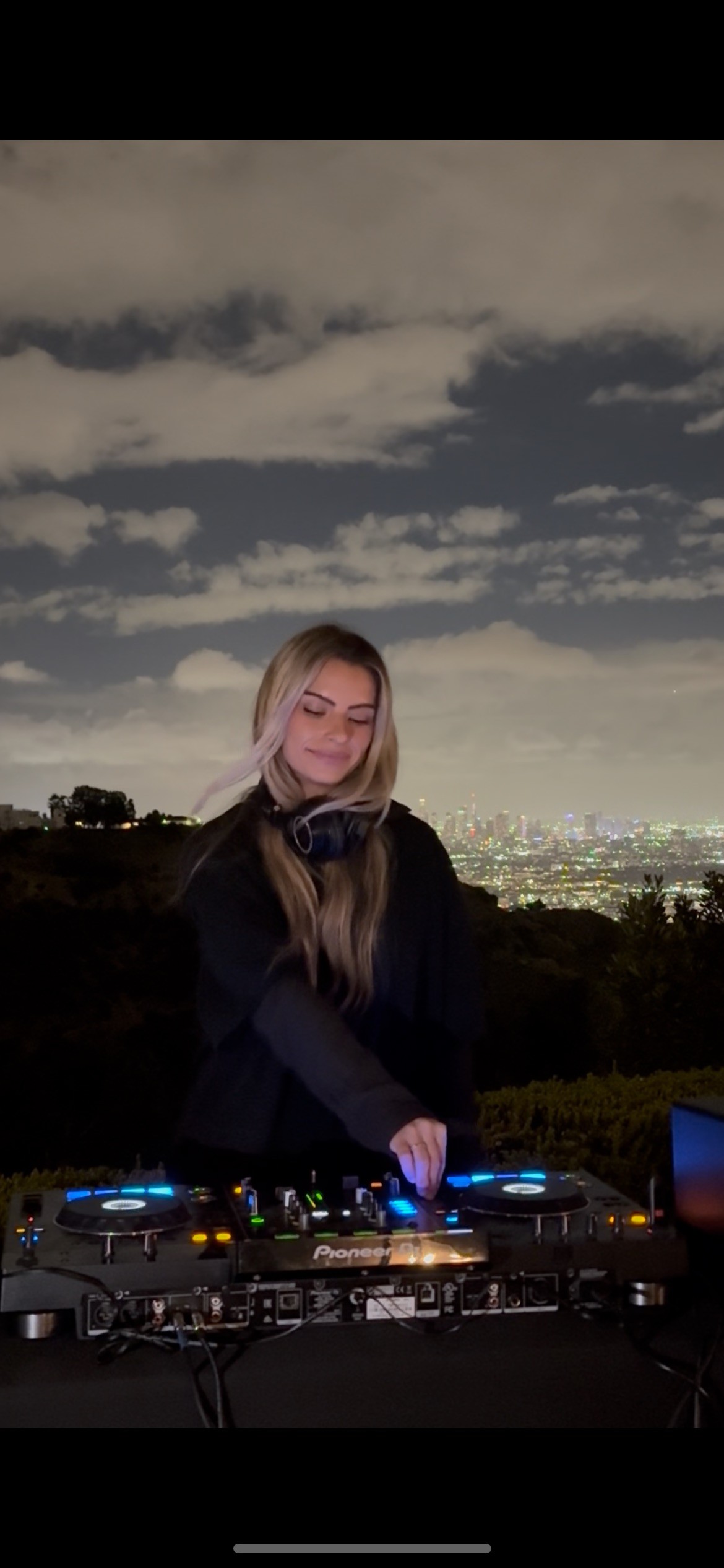 Béatrice Dupont DJing at night overlooking city lights