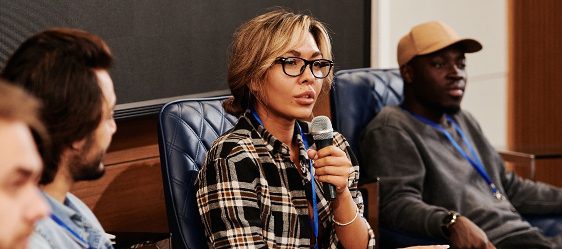 Woman with a glass holding mic giving speech