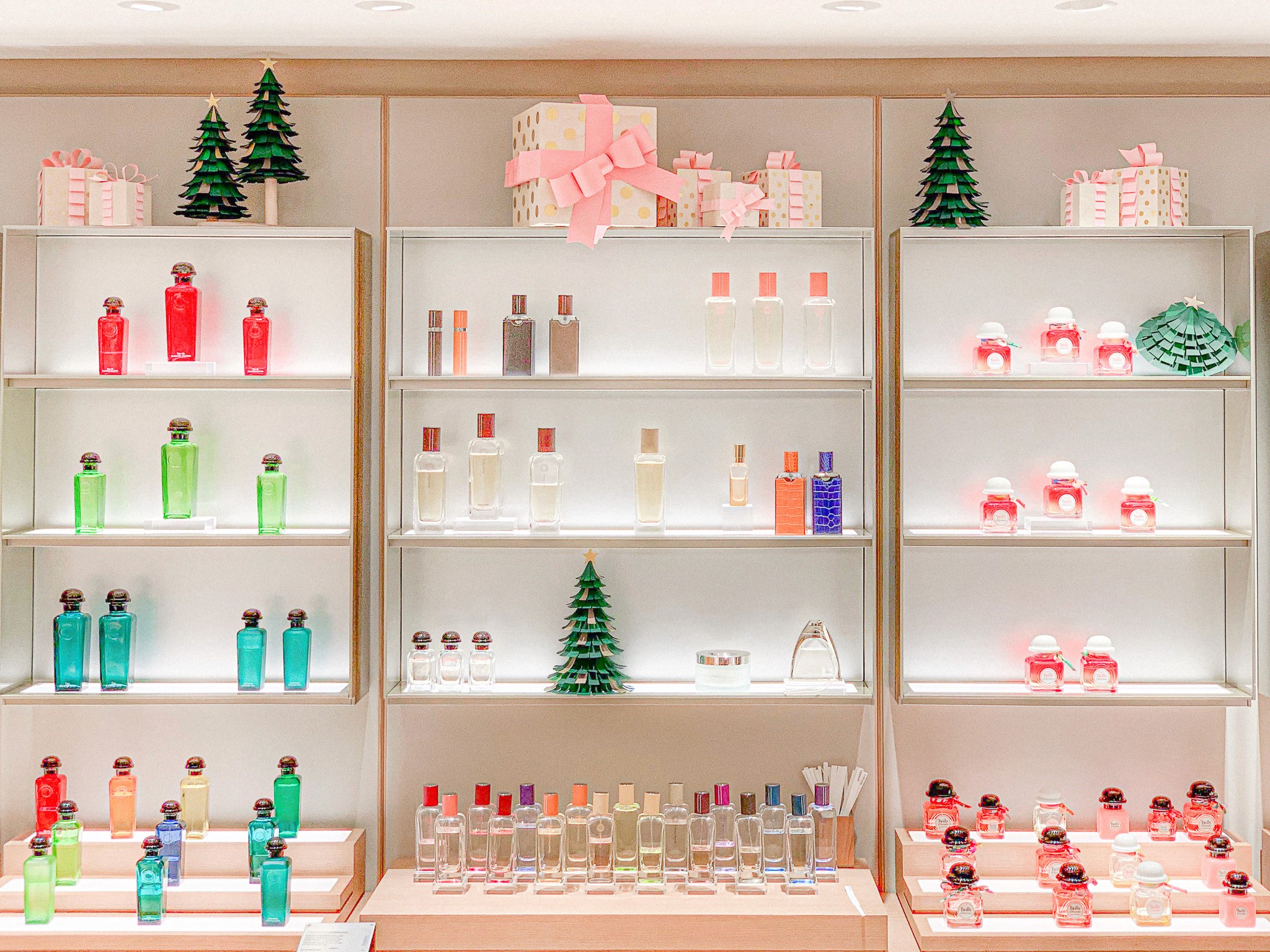 Comprehensive in-store fragrance display for the Hermès holiday scenography, featuring symmetrical shelving units adorned with paper Christmas trees and gift box props, designed by WM Paris.