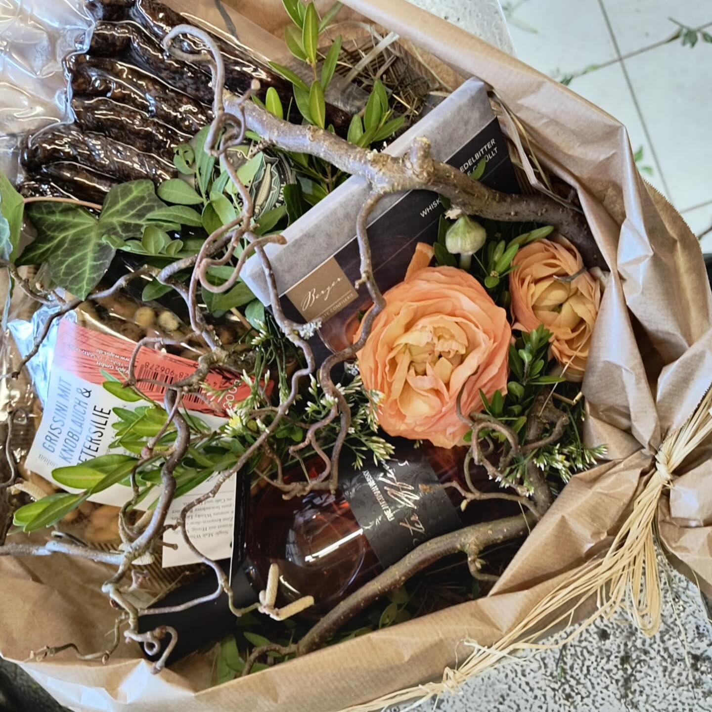 Blumenstrauß mit Rosen, einem Wein und Schokolade.