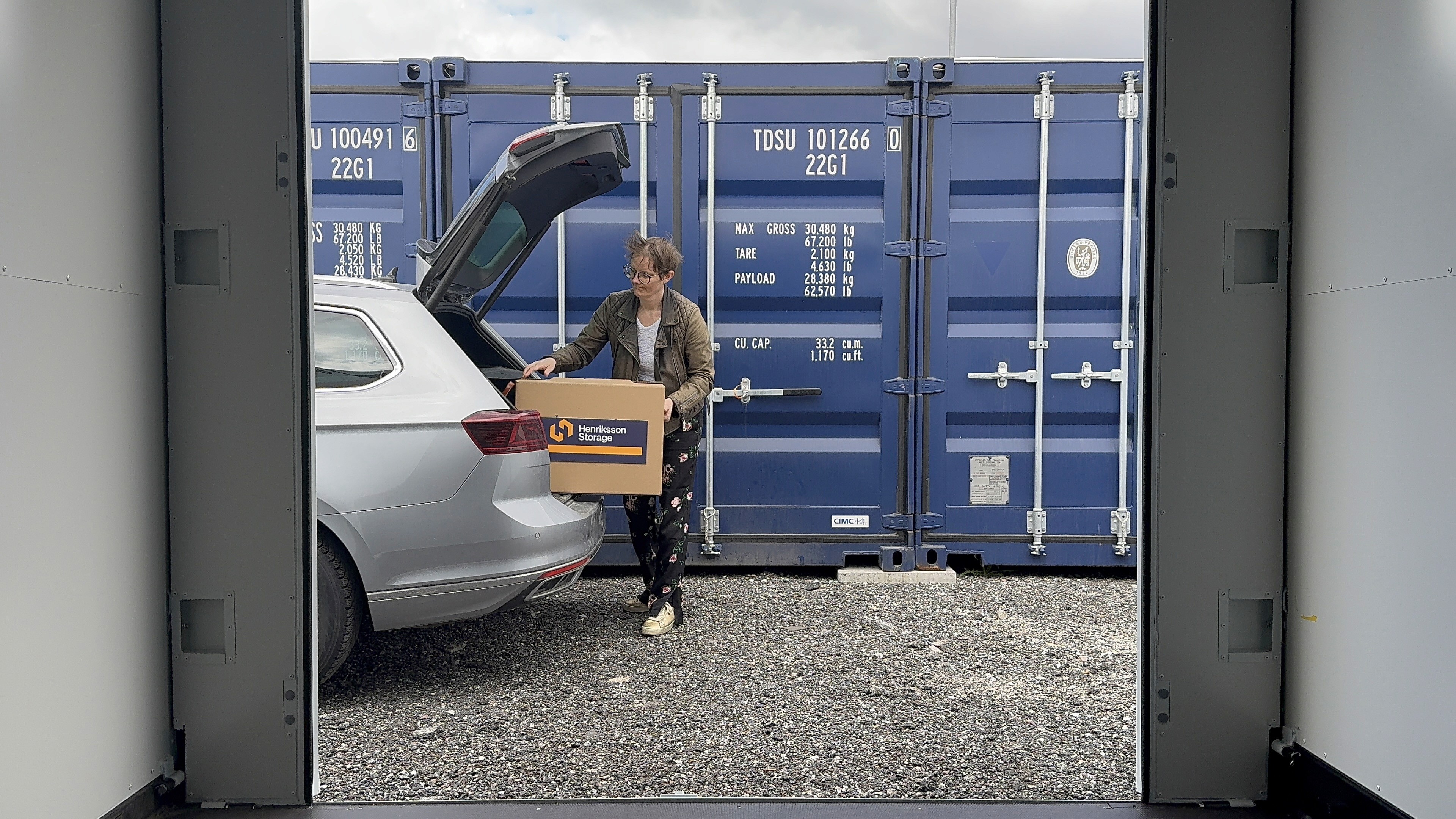 Kund lastar flyttkartong från bil till blå containerförråd hos Henriksson Storage