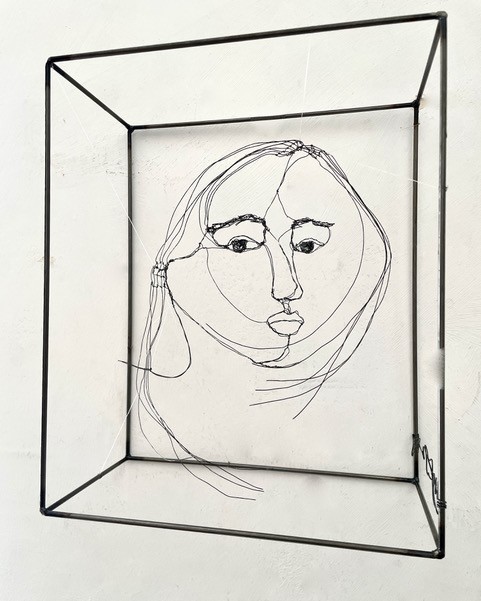Sculpture en fil de fer représentant le visage d'une femme dans un cadre en fil de fer, vue détaillée de face