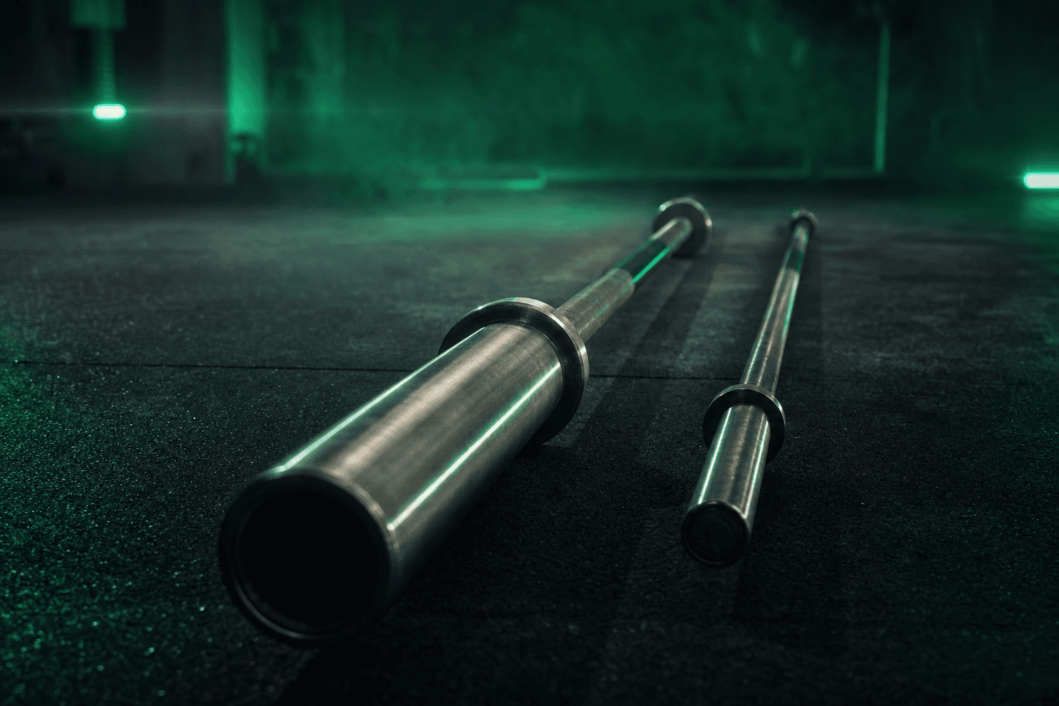 Two barbells side by side comparing a thick Olympic bar with rotating sleeves against a thinner one-inch standard bar
