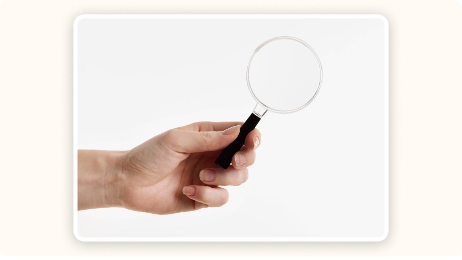 Hand holding a magnifying glass