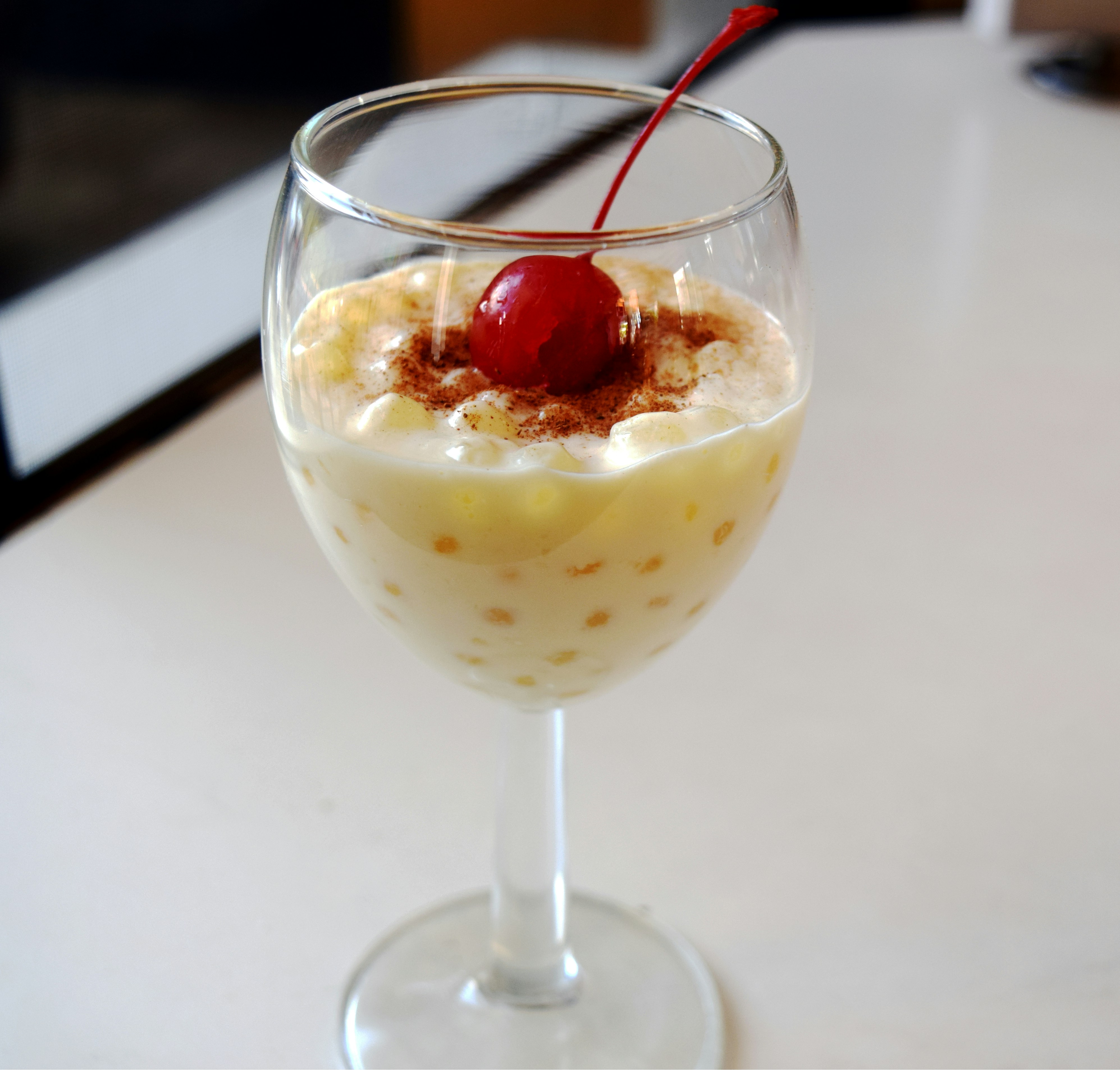 a dessert in a wine glass with a cherry on top