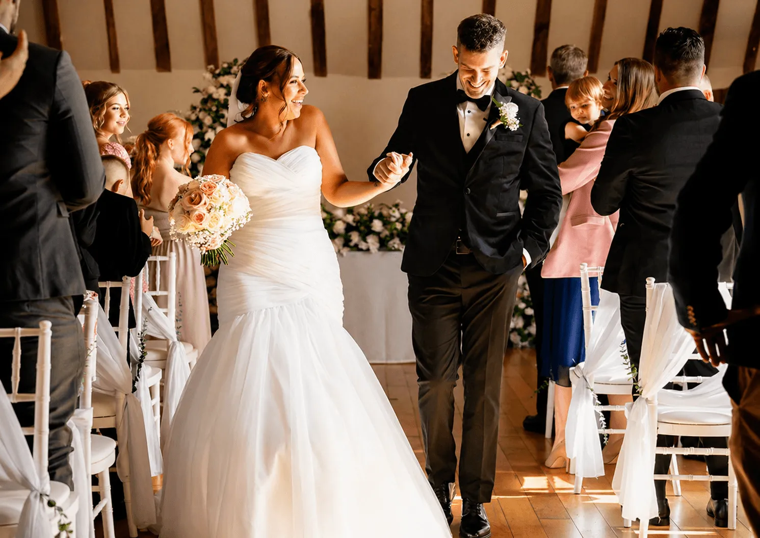 Wedding portrait: Bride in lace gown, veil, and tiara, holding bouquet. Groom in black tuxedo.