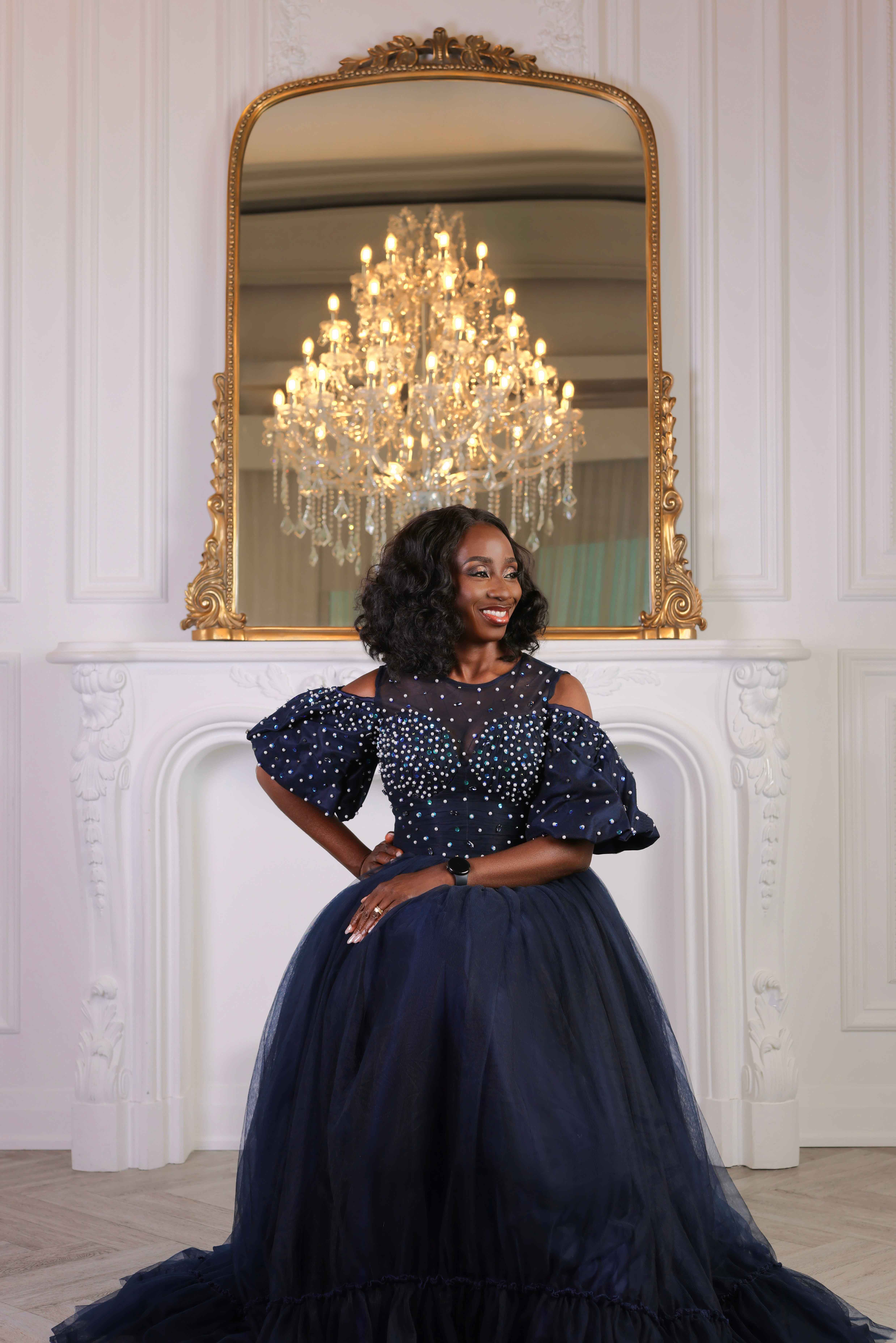 Woman posing in a formal gown beneath a chandelier