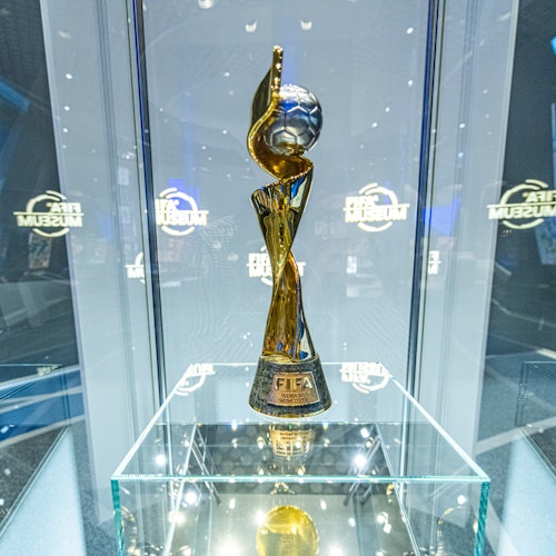 Golden FIFA Women’s World Cup trophy displayed in a glass case, with FIFA Museum signage in the background.