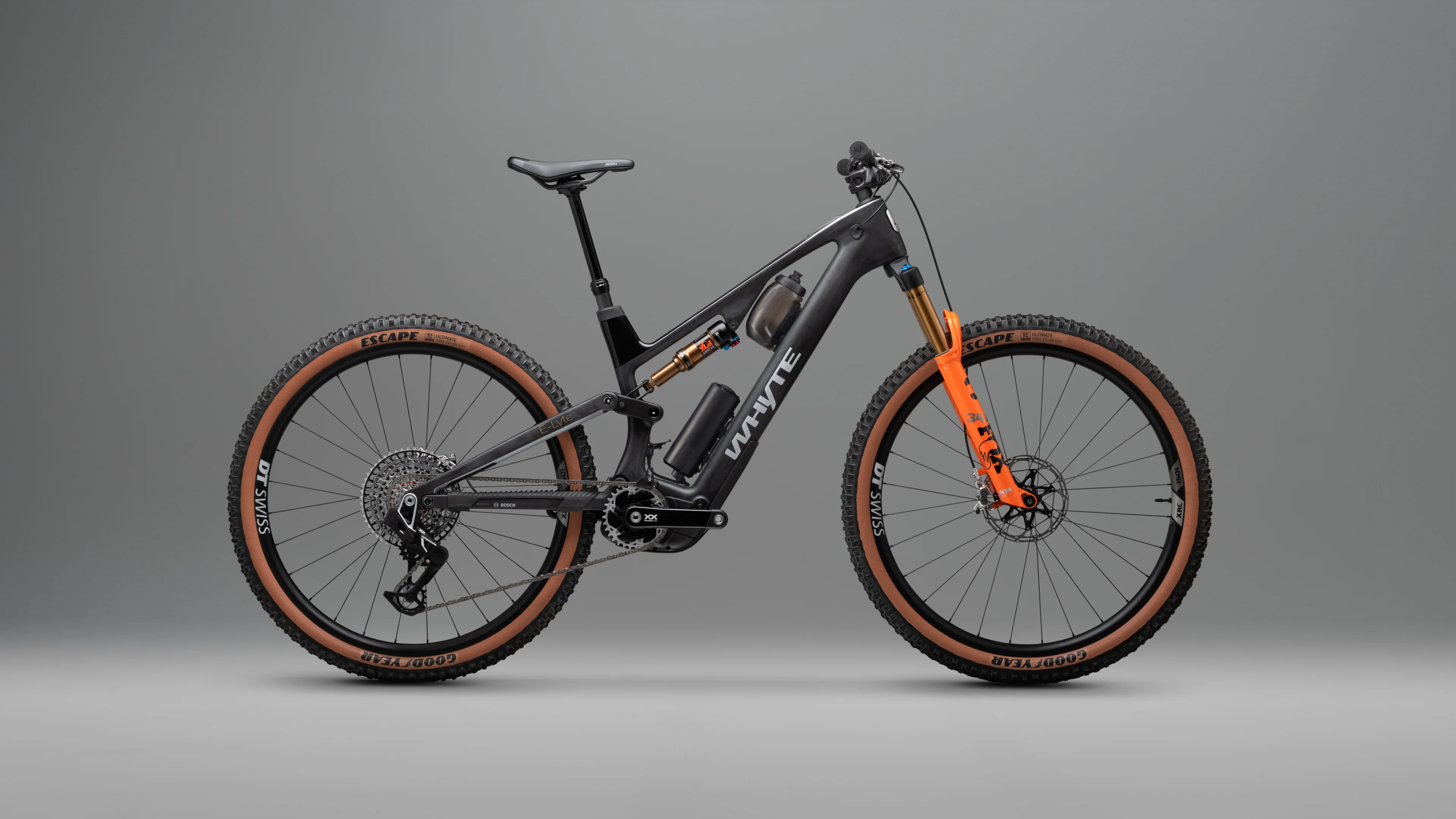 Full view of Elyte electric mountain bike in studio lighting, showcasing carbon frame, orange suspension fork, and integrated e-MTB battery system.