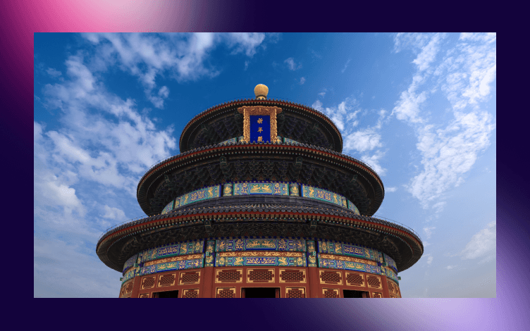 Multi-tiered ornate structure with traditional blue and gold patterns against a cloudy sky background, symbolizing architectural beauty in a religious or cultural context.