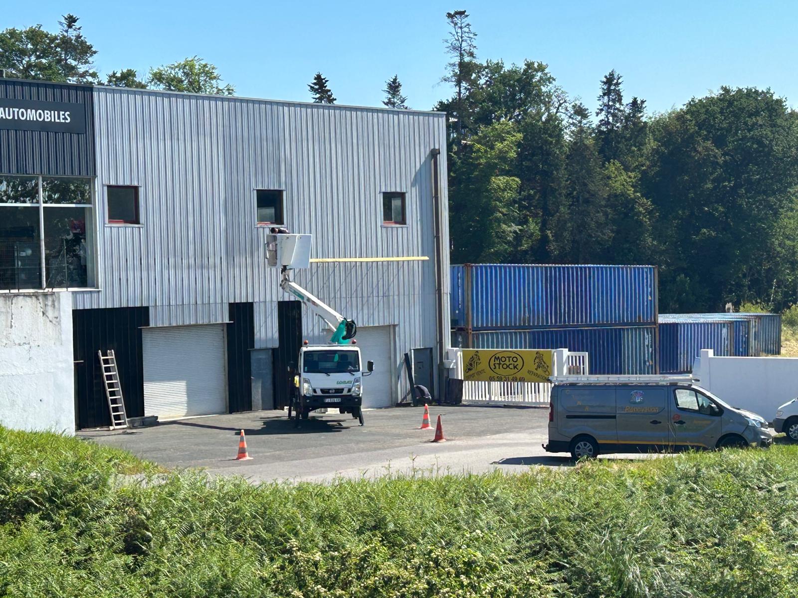 Peintre en bâtiment sur nacelle pour le ravalement de façade d'un local commercial.