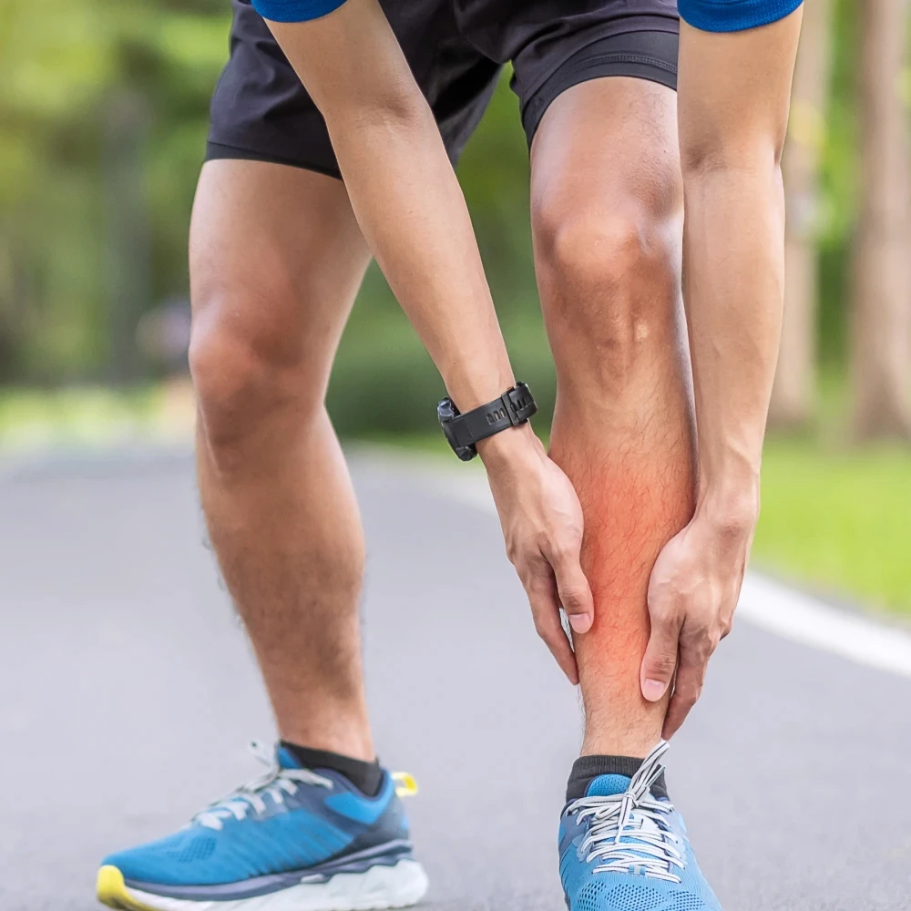 A man in running attire holding his red lower leg