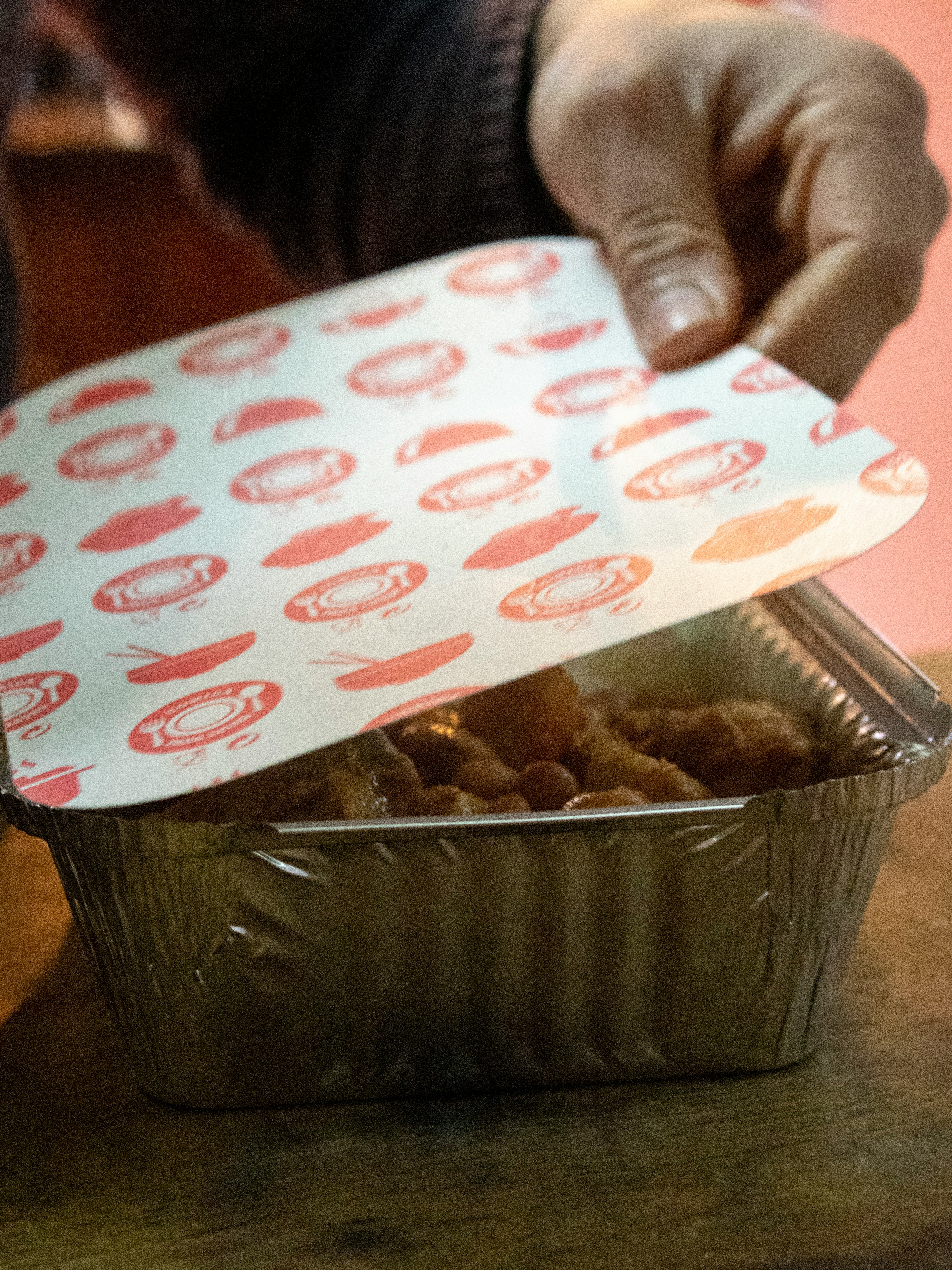 a person holding a piece of paper over a container of food