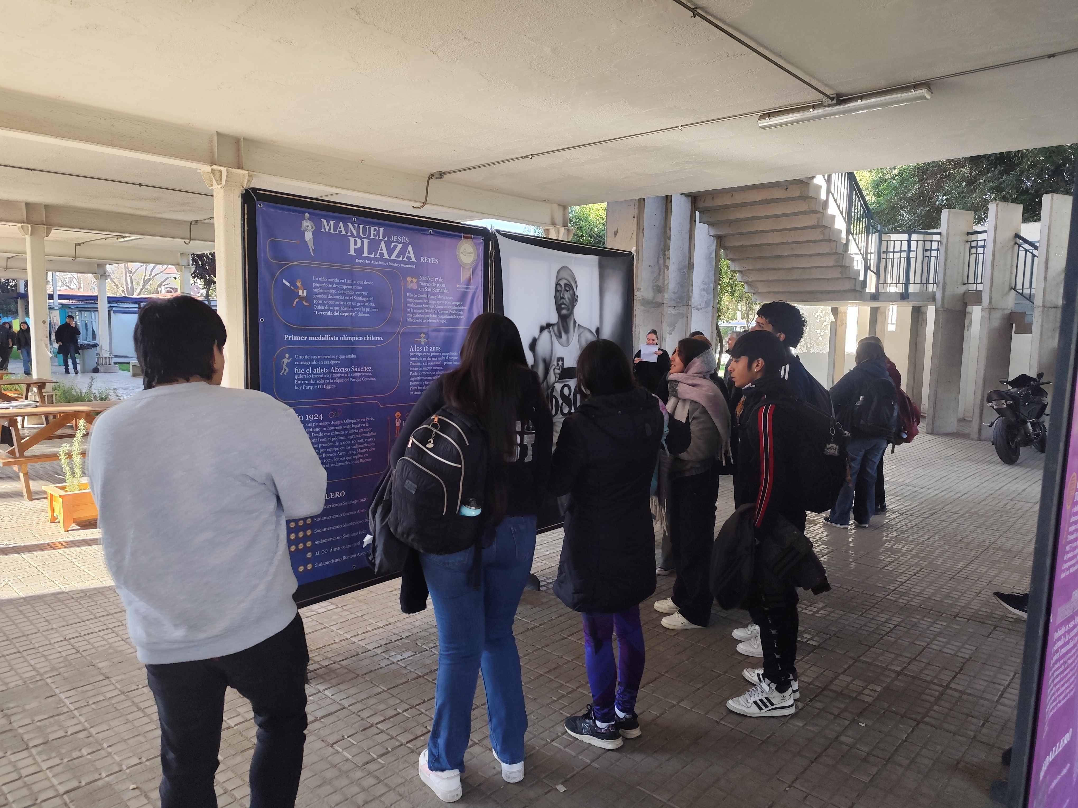 Asistentes observando la pintura de Manuel Plaza, medallista olímpico chileno, en la exposición Leyendas del Deporte en USACH.