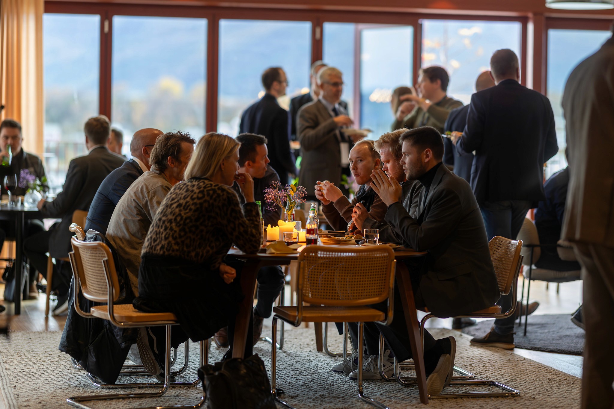 A group of people mingling at an event, with one man looking upwards, appearing deep in thought.