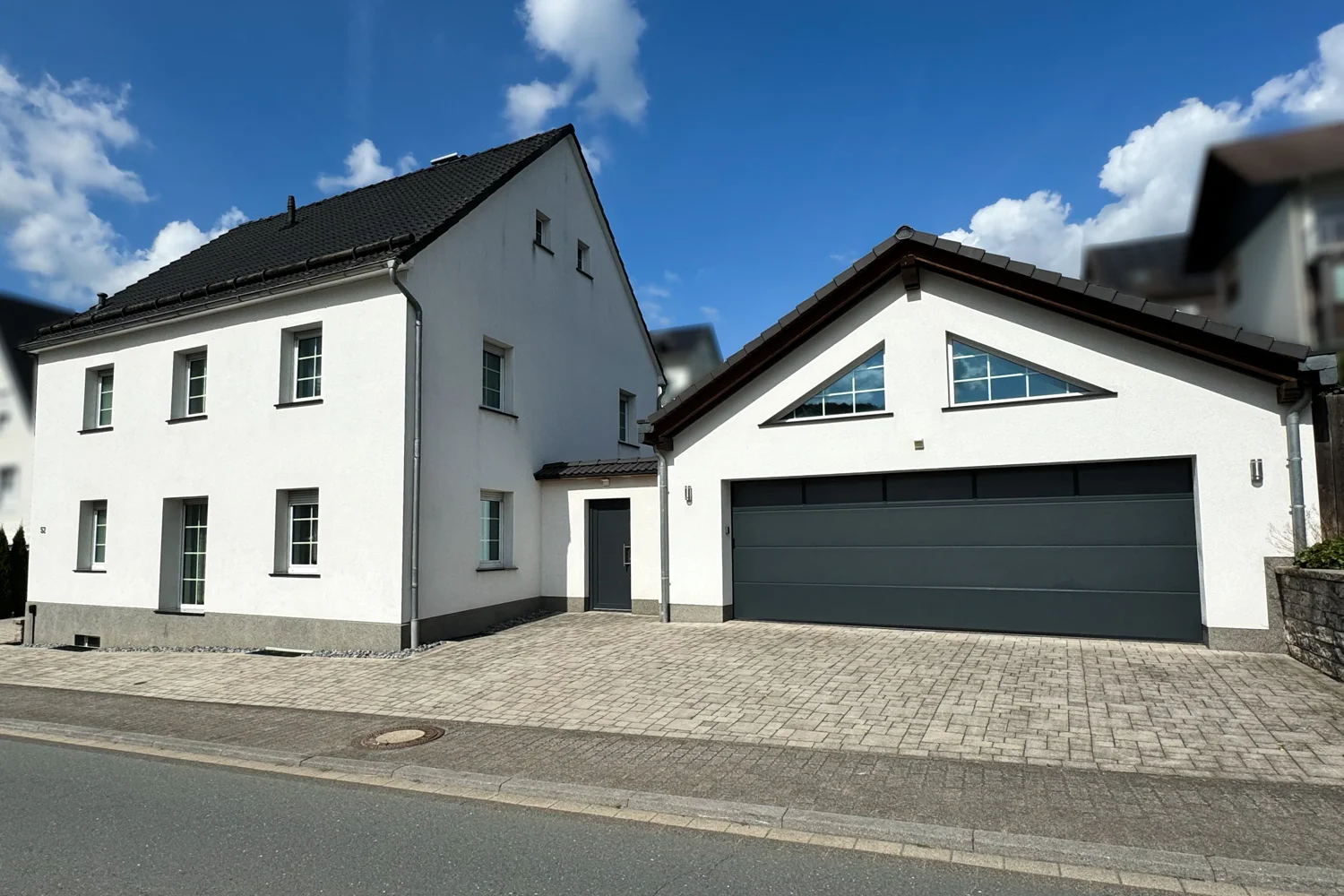 Gepflasterte Einfahrt mit modernem Wohnhaus