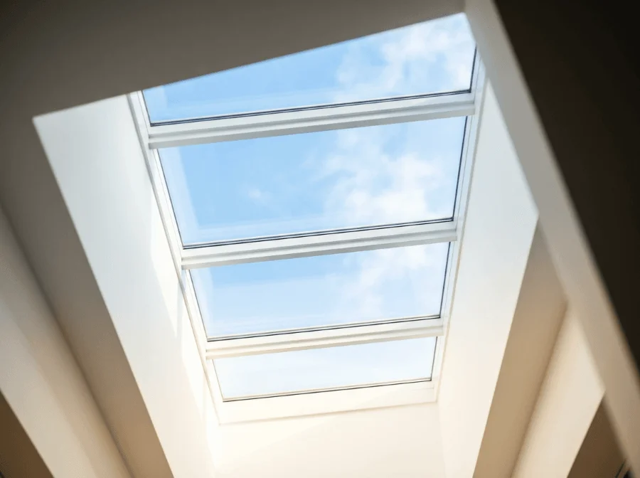 Blick nach oben durch ein großes, sauberes vierteiliges Dachfenster in einen blauen Himmel mit leichten Wolken