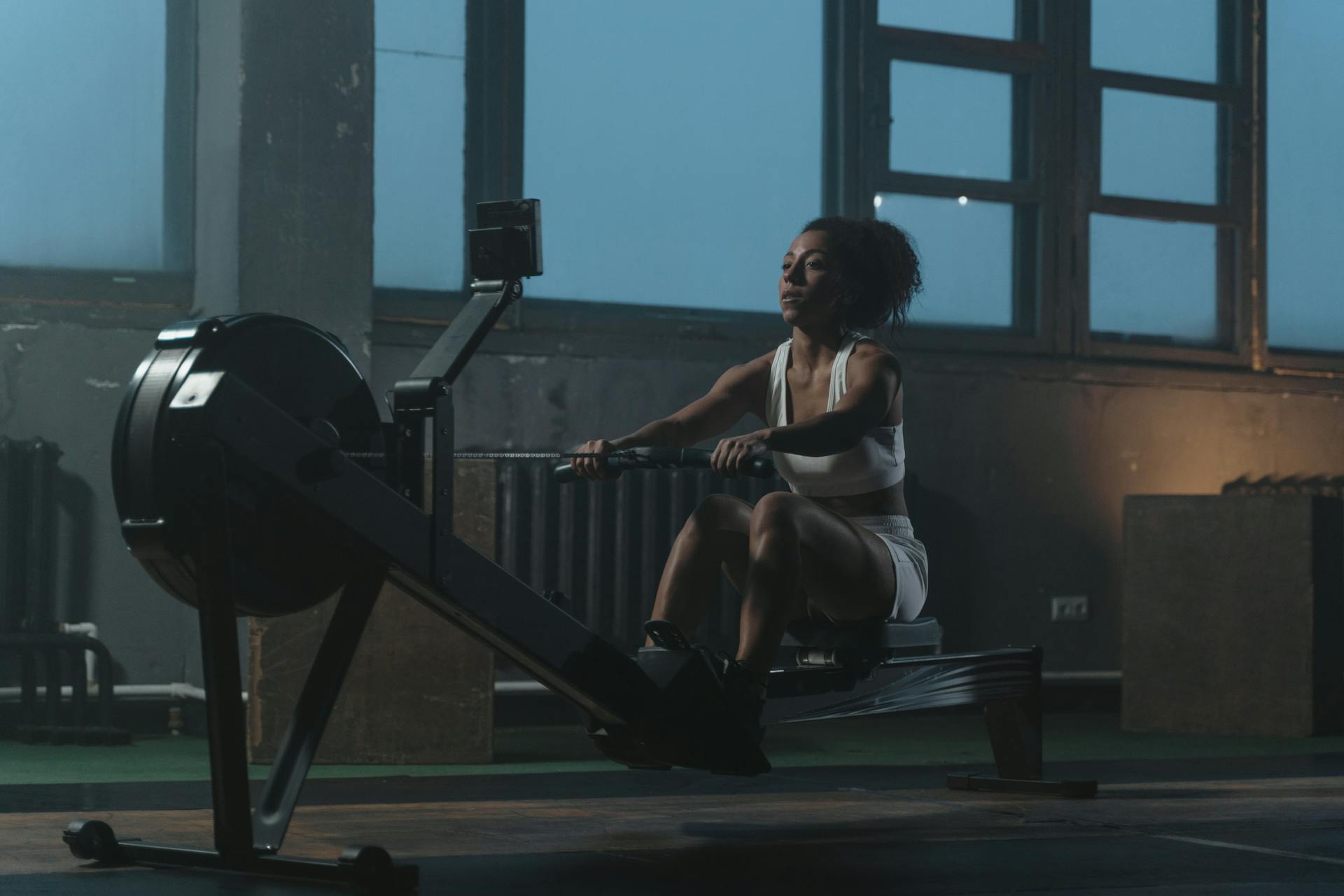 Woman stretching with arms overhead in a gym.